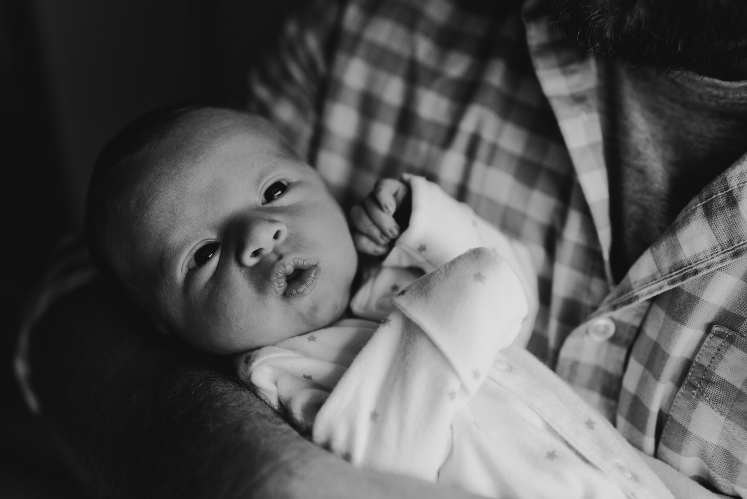 Newborn baby being held by dad close to his chest