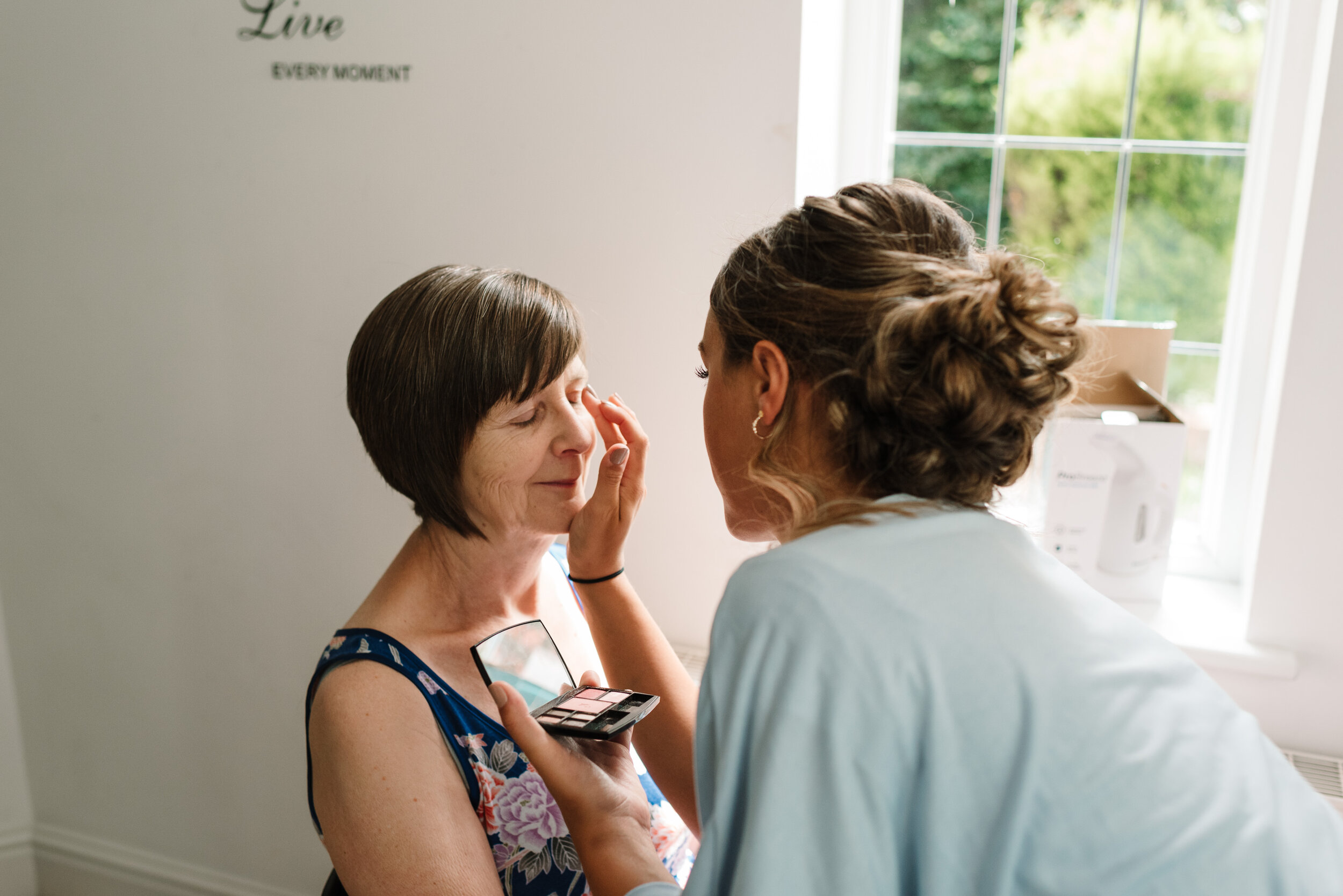 Bridesmaid doing the mother of the bride's make up