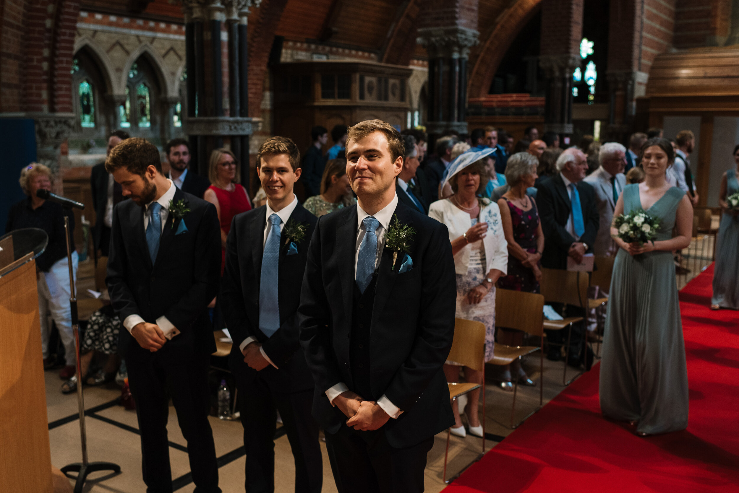 Groom and ushers waiting for bride to walk up church aisle