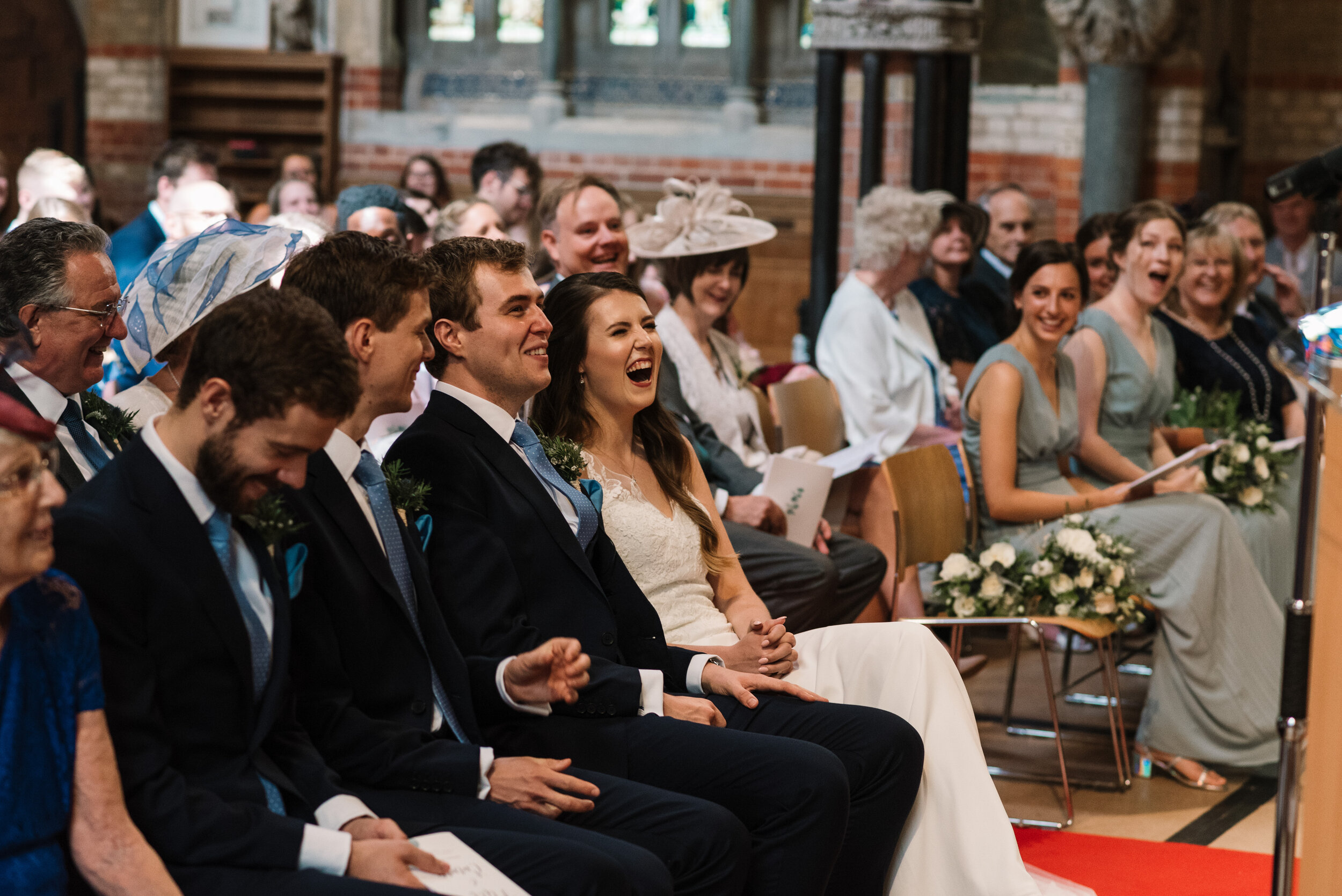 Bride and groom seated at front of church and laughing