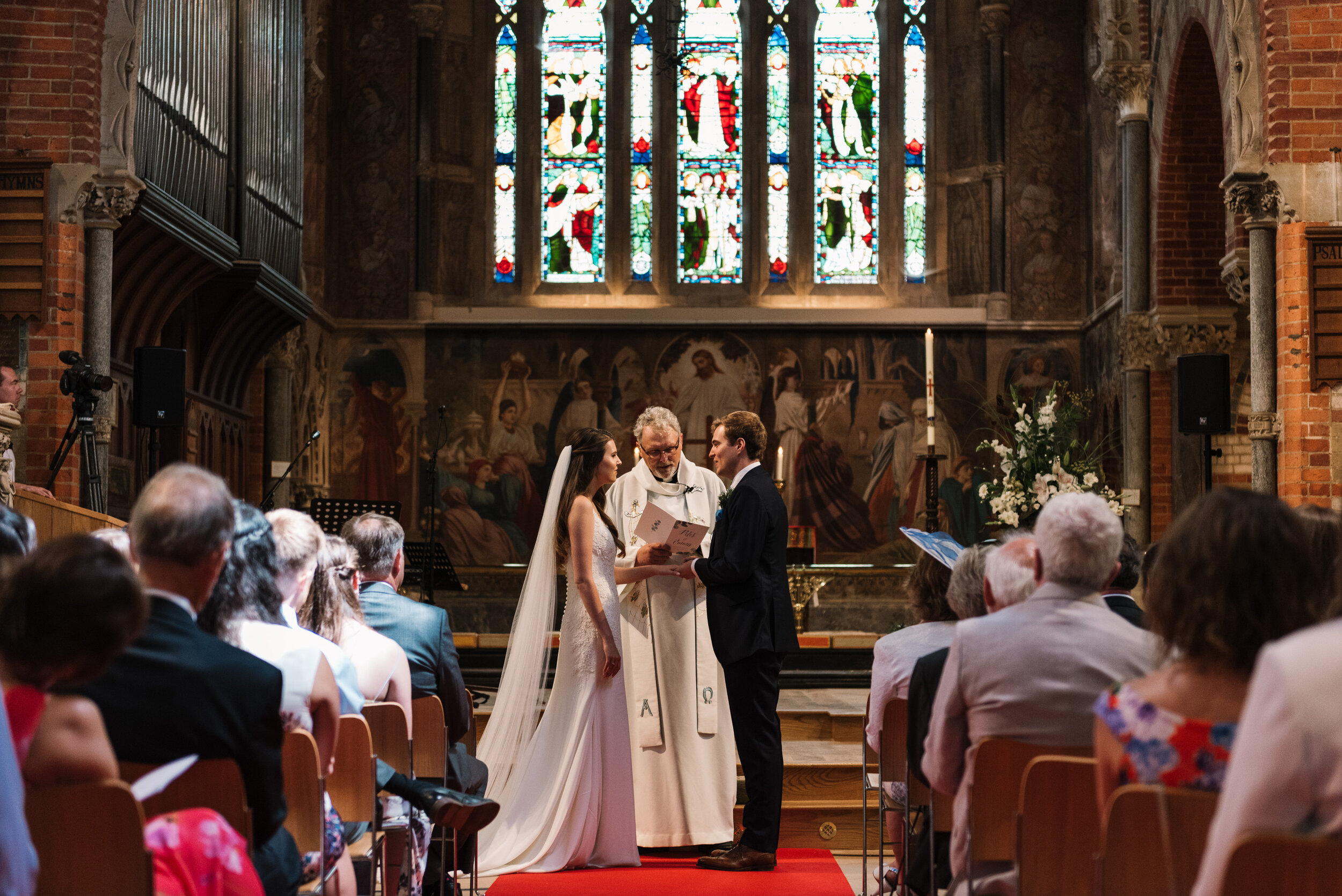 Bride and groom holding hands at front of church, whilst doing vows