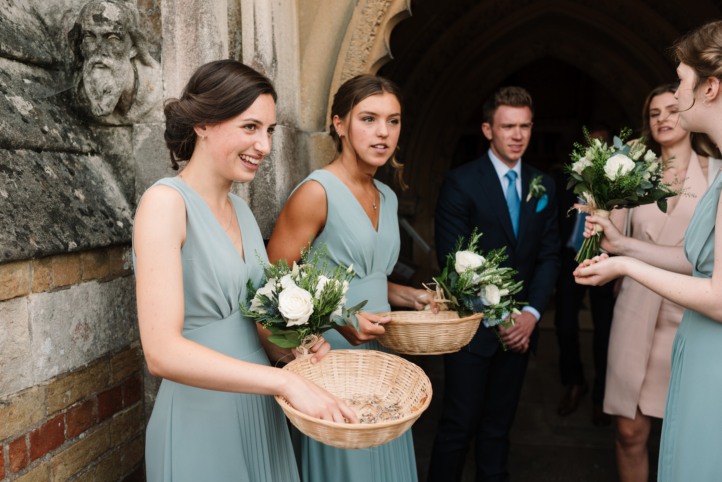 Bridesmaids handing out confetti from baskets to guests outside church