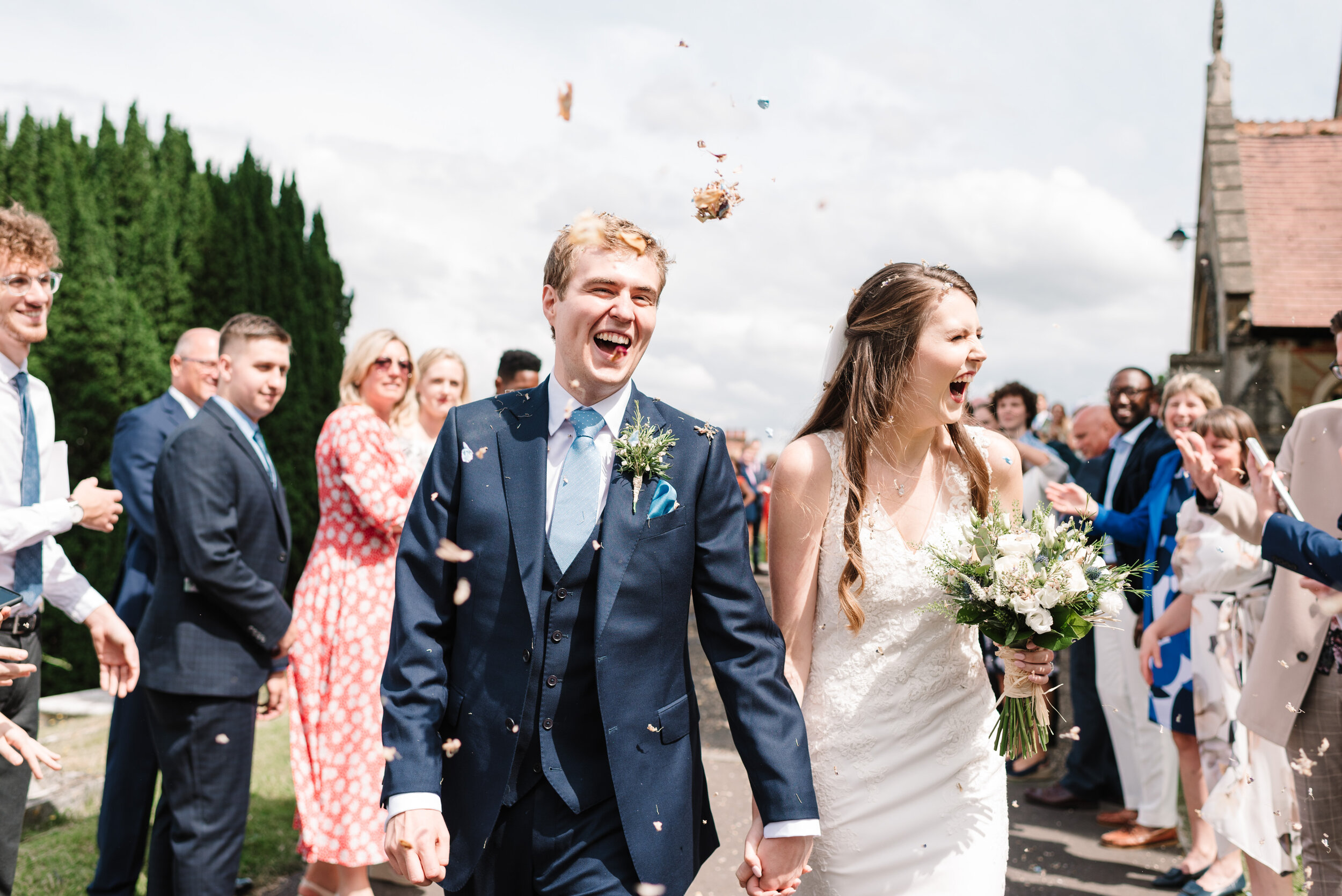 Guests throwing confetti at bride and groom