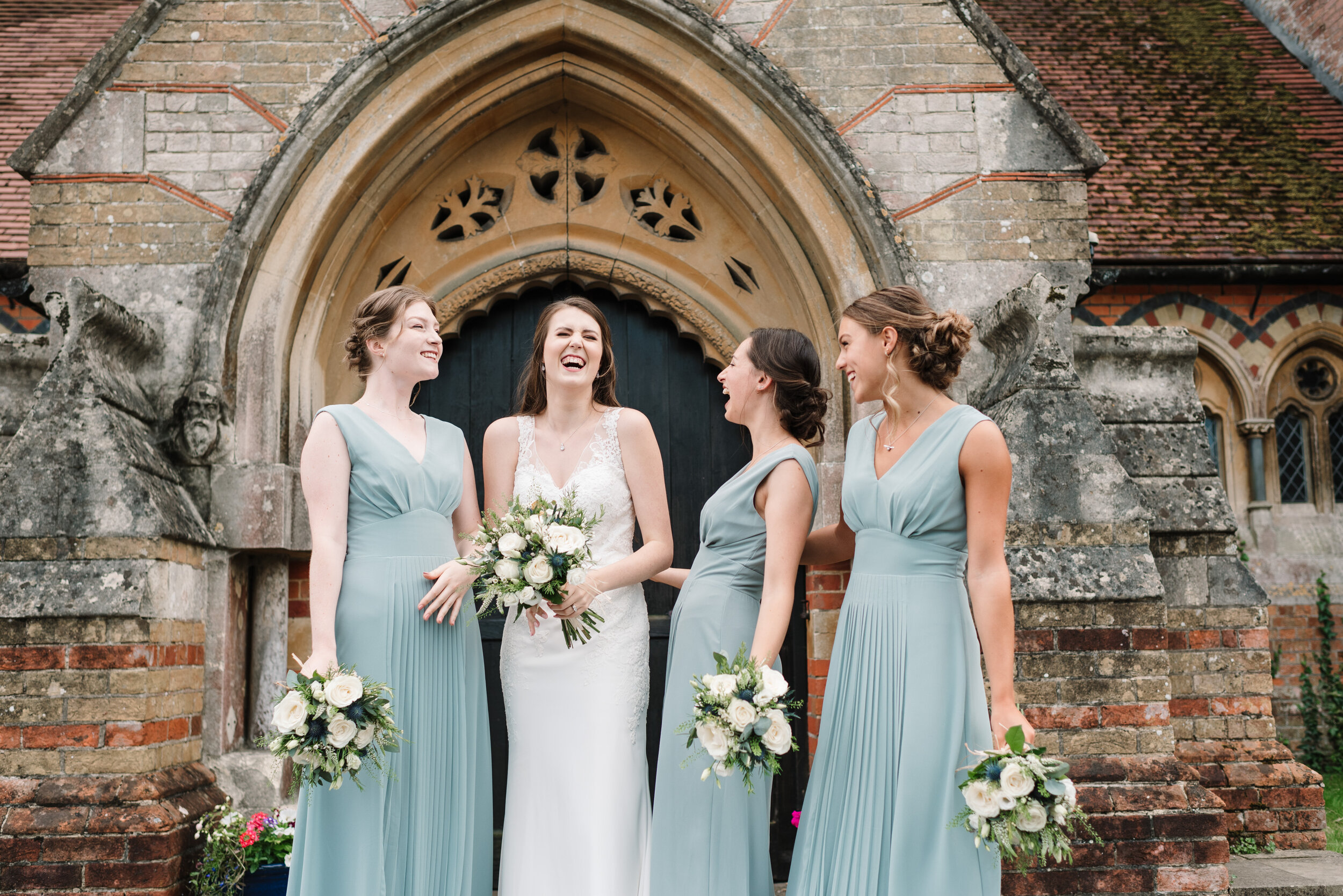 Bride and three bridesmaids laughing outside church
