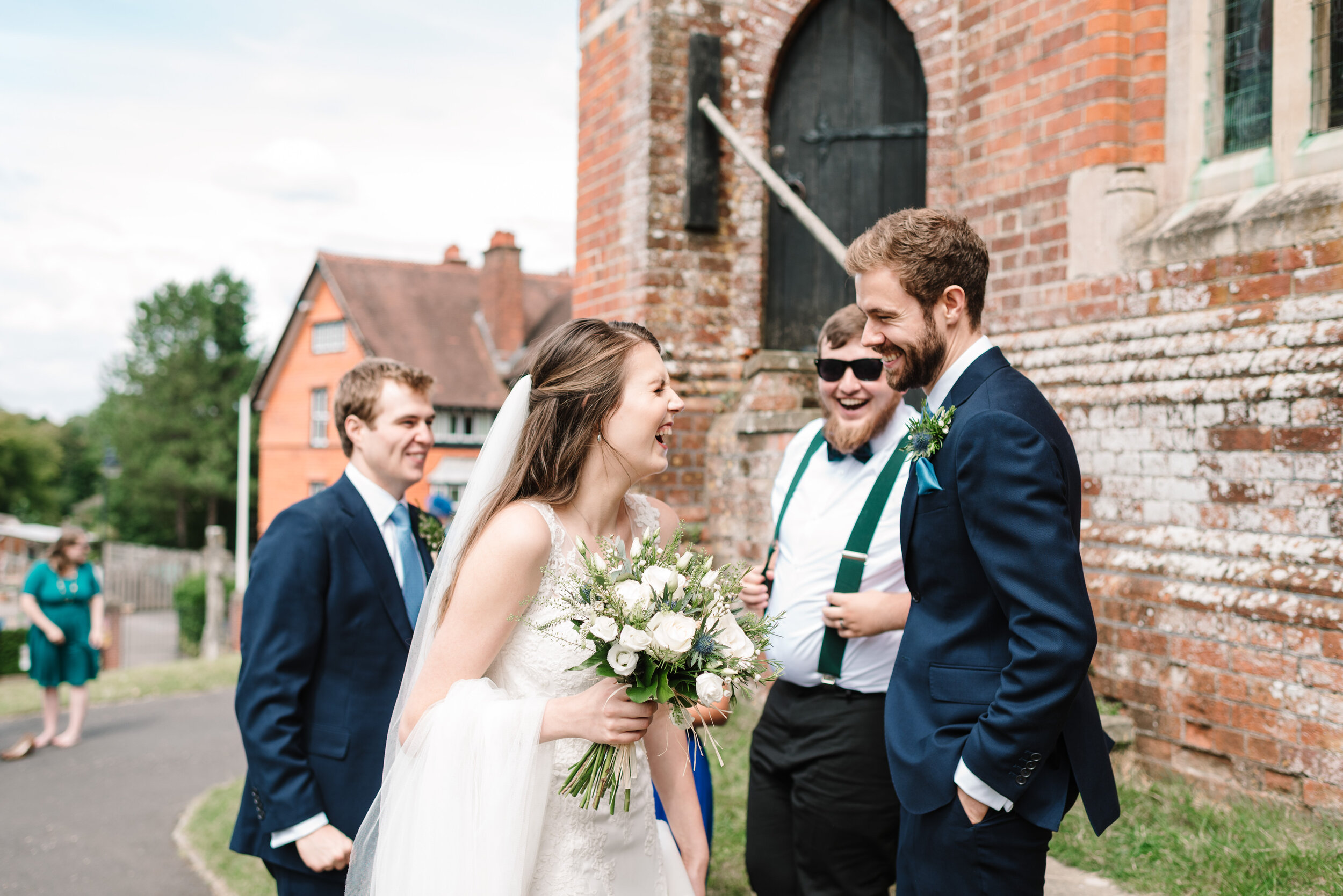 Bride laughing with a groomsman outside church