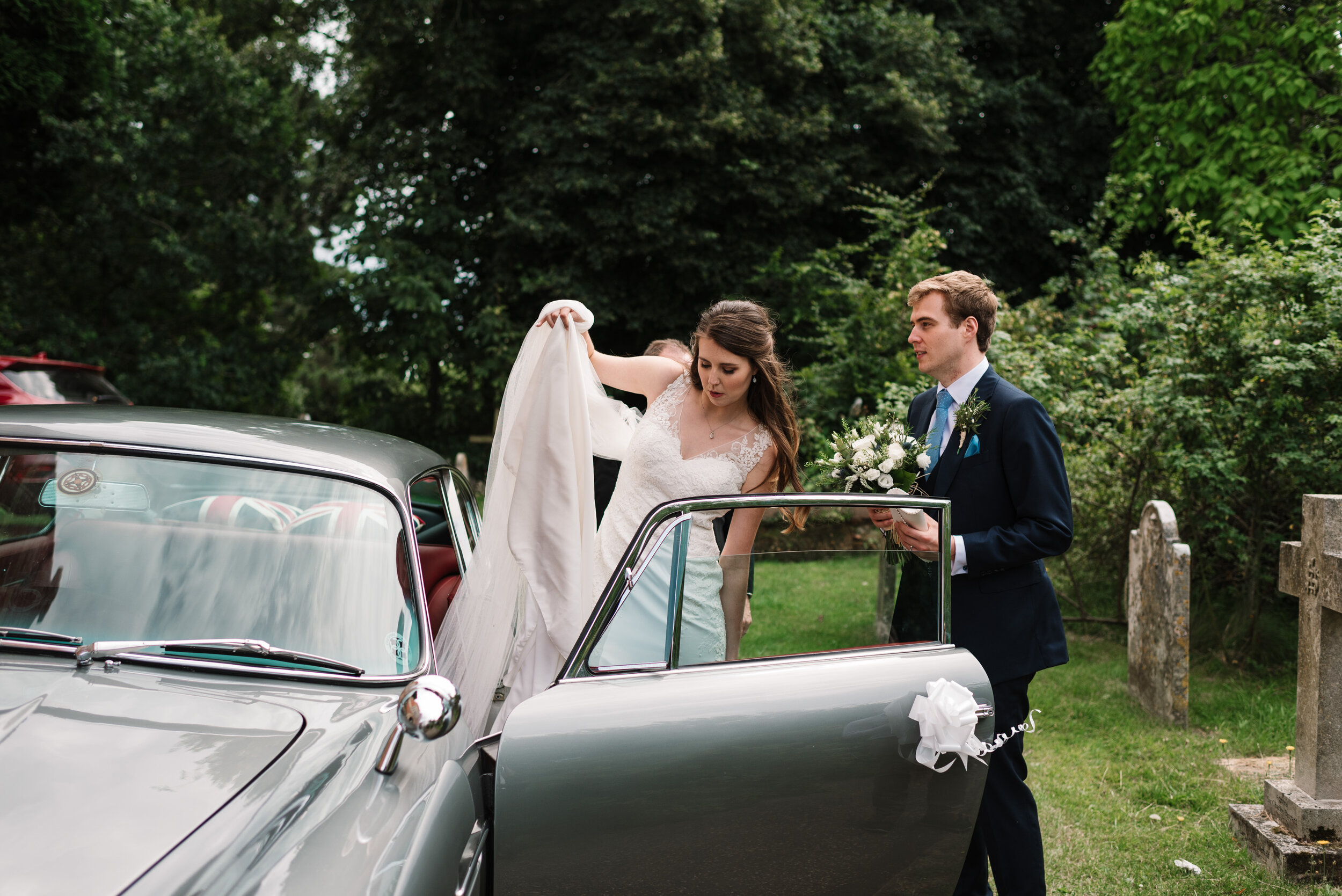 Bride and groom getting into Aston Martin DB5