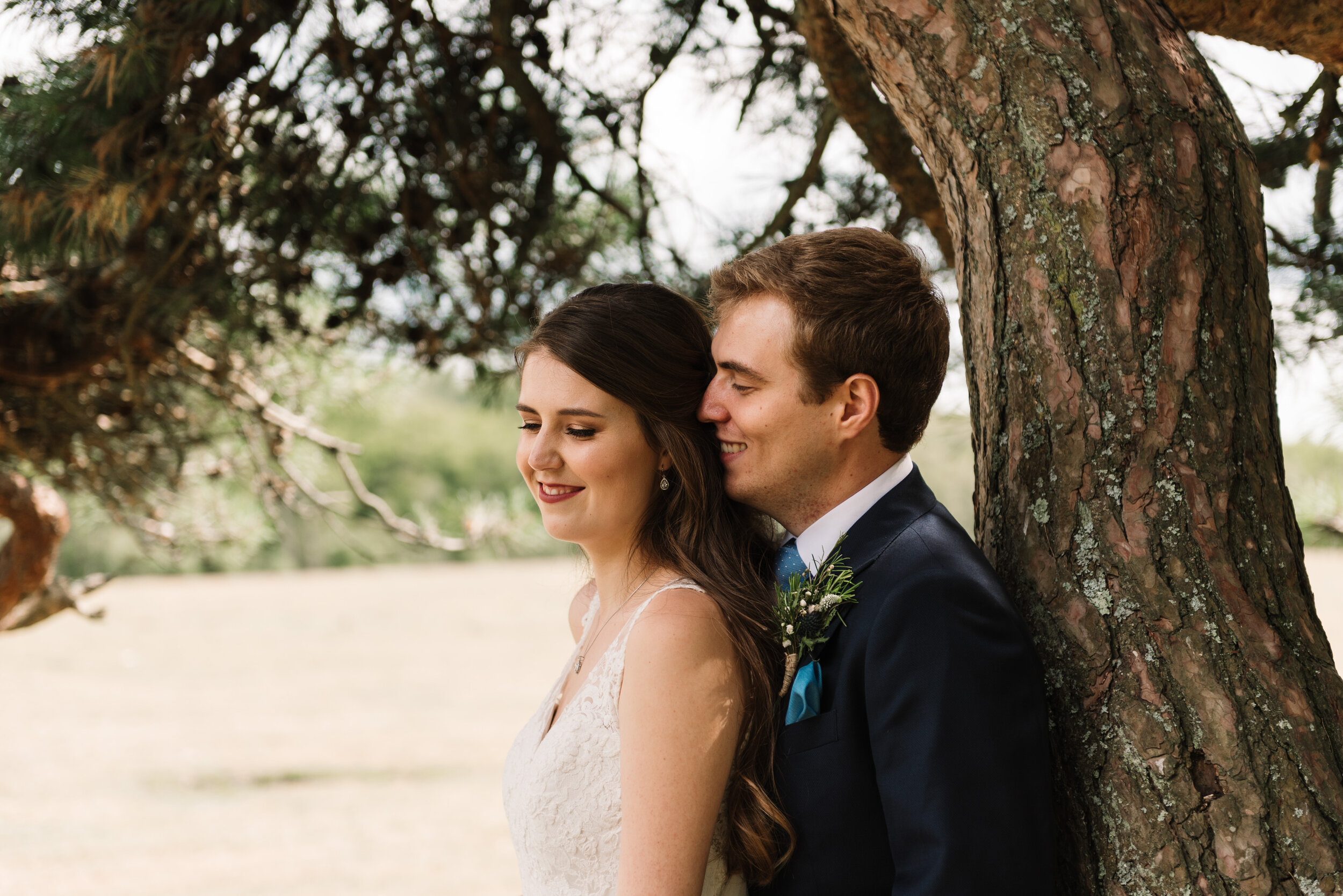 Close-up of bride and groom's faces by tree in the New Forest