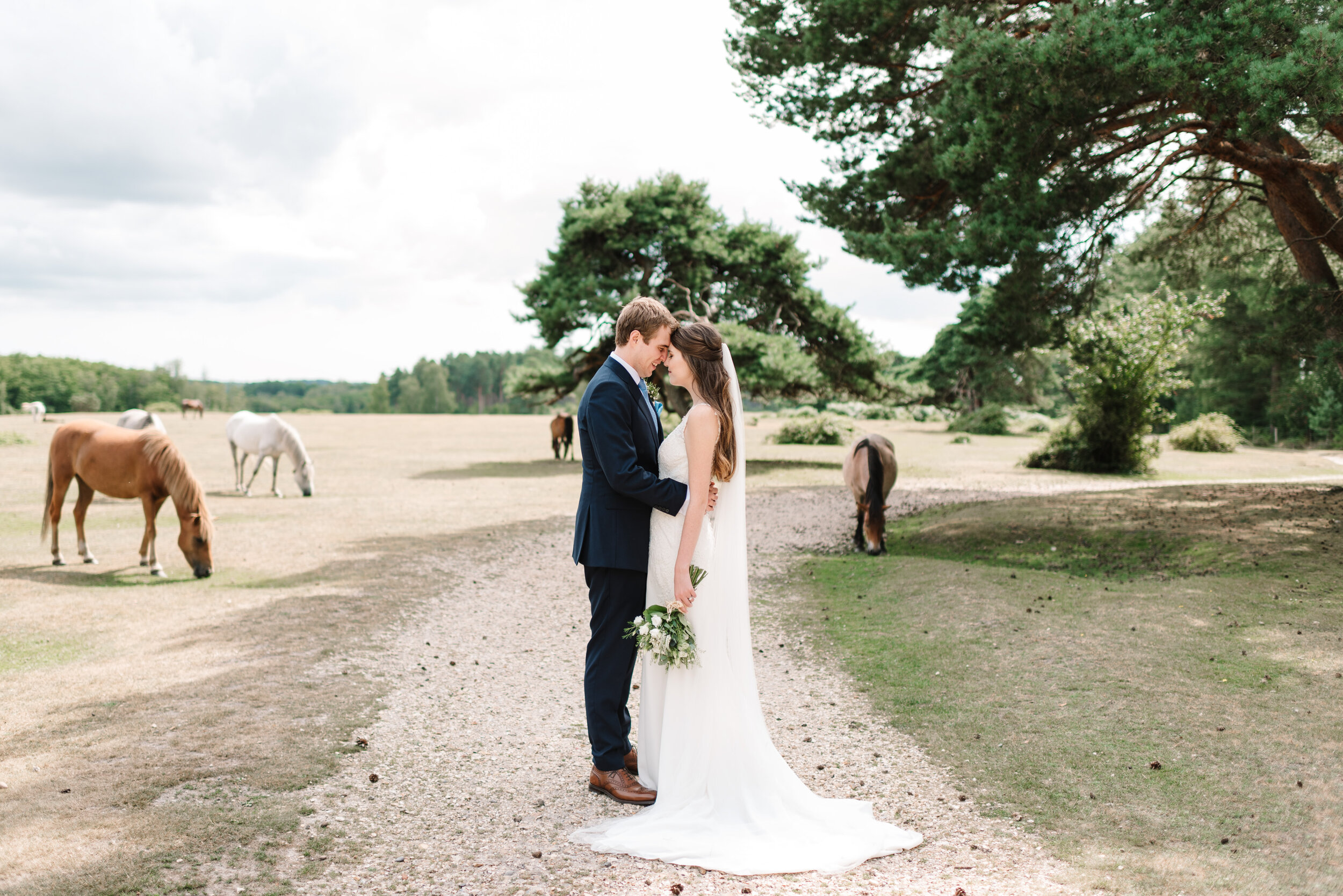 Bride and groom facing each other surrounded by New Forest horses