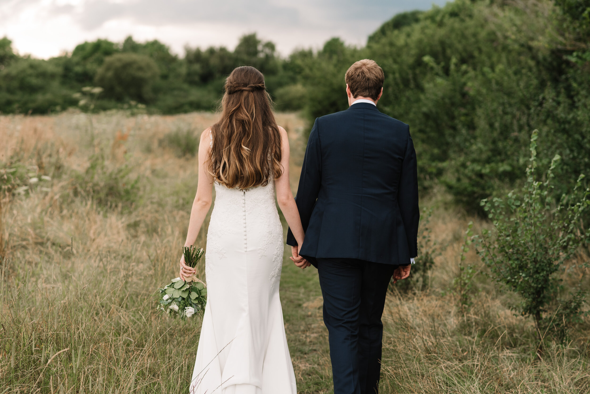 Bride and groom walking away in field at Hanger Farm wedding