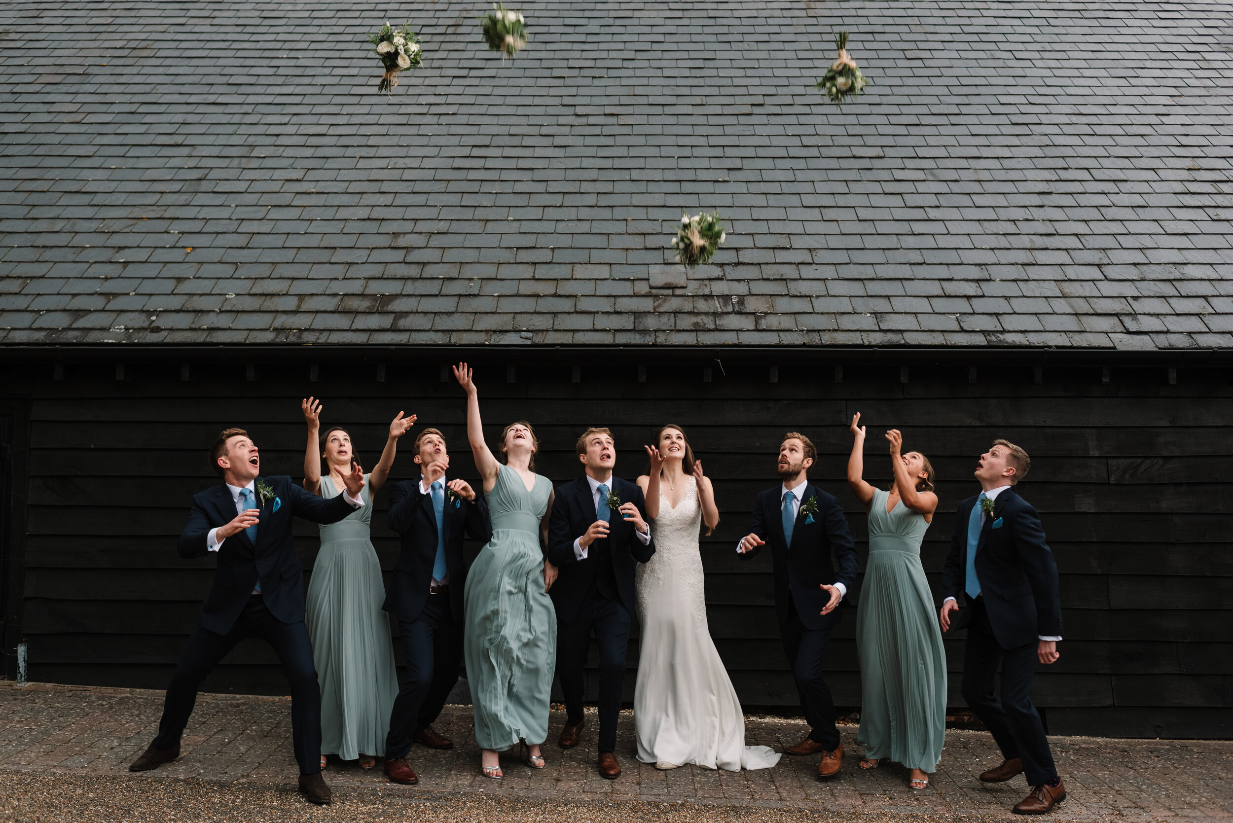 Bridesmaids throwing bouquets in the air for groomsmen to catch