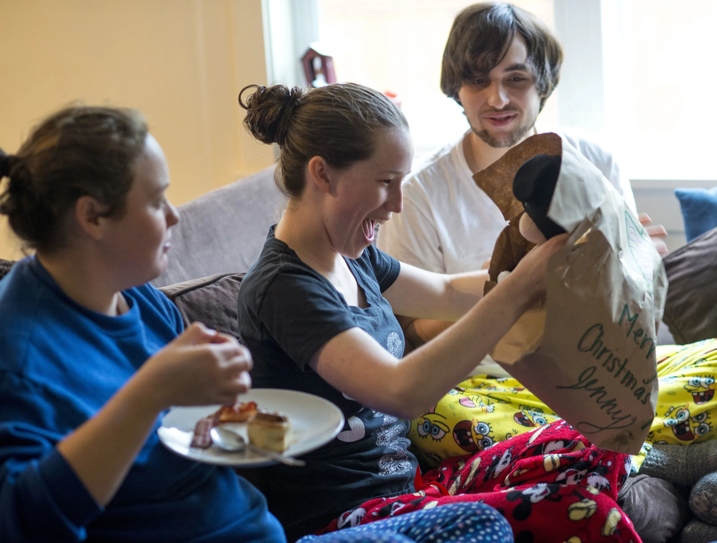 Jenny Horn is delighted by a Christmas present given to her by Hannah Giardina (left) while her boyfriend Harrison Allen-Sutter looks on. The University of Oregon students celebrate early so that they can be together for the holidays.