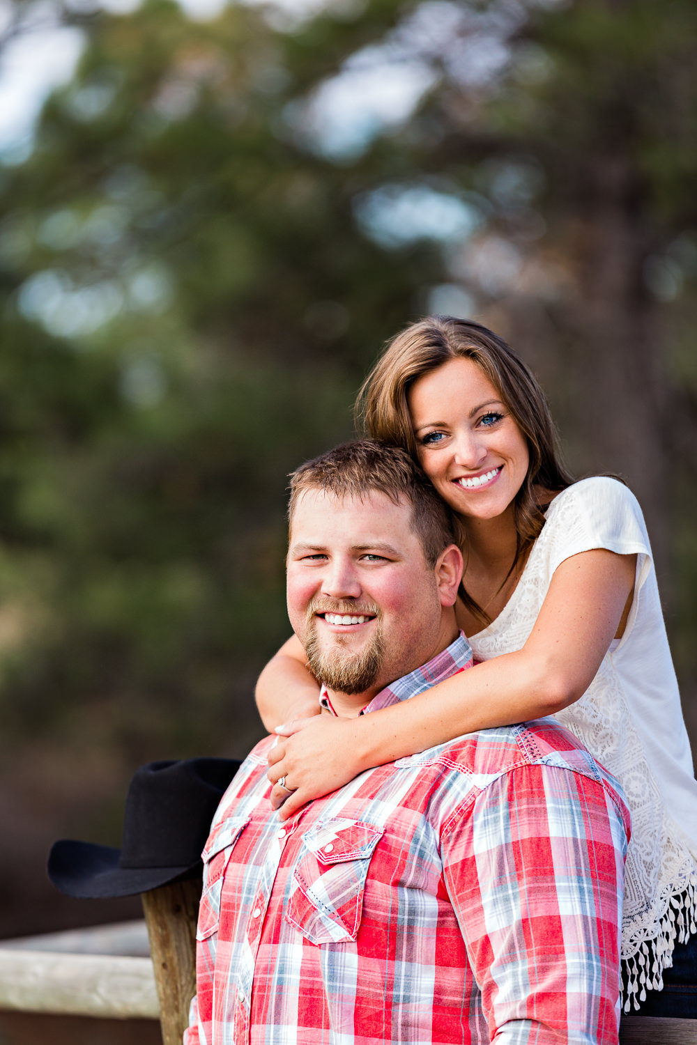 billings-montana-engagement-session-woman-stands-on-fence-behind-man.jpg