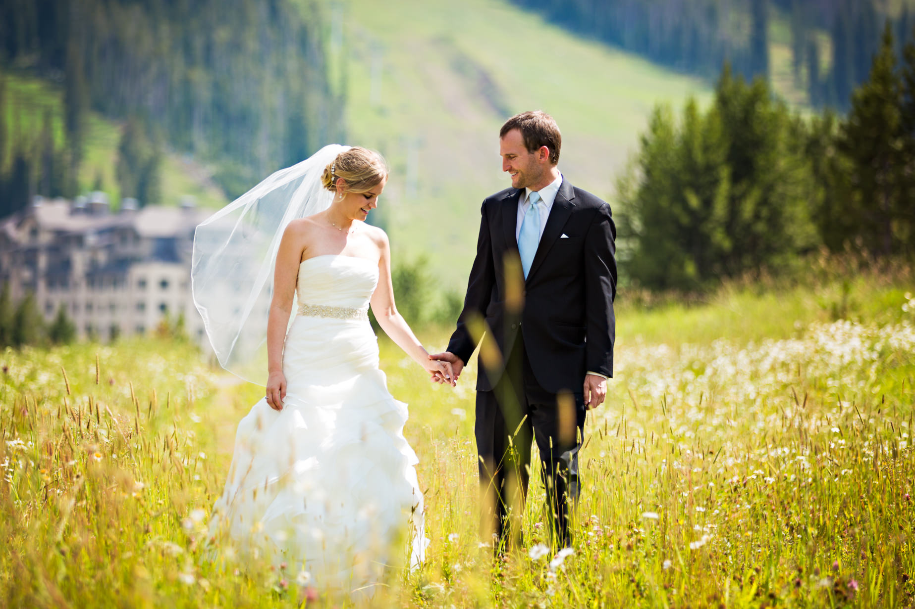 big-sky-resort-wedding-bride-groom-hold-hands-in-field.jpg