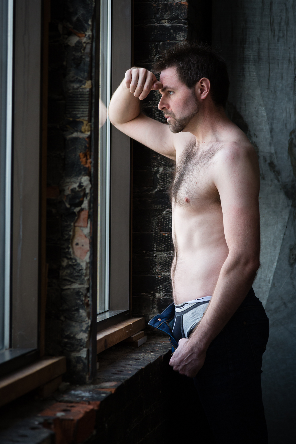 montana-male-boudoir-photoshoot-shirtless-man-leans-arm-on-window.jpg
