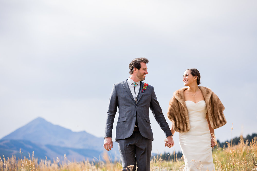 big-sky-montana-gallatin-riverhouse-wedding-bride-groom-walking-through-mountain-meadow.jpg