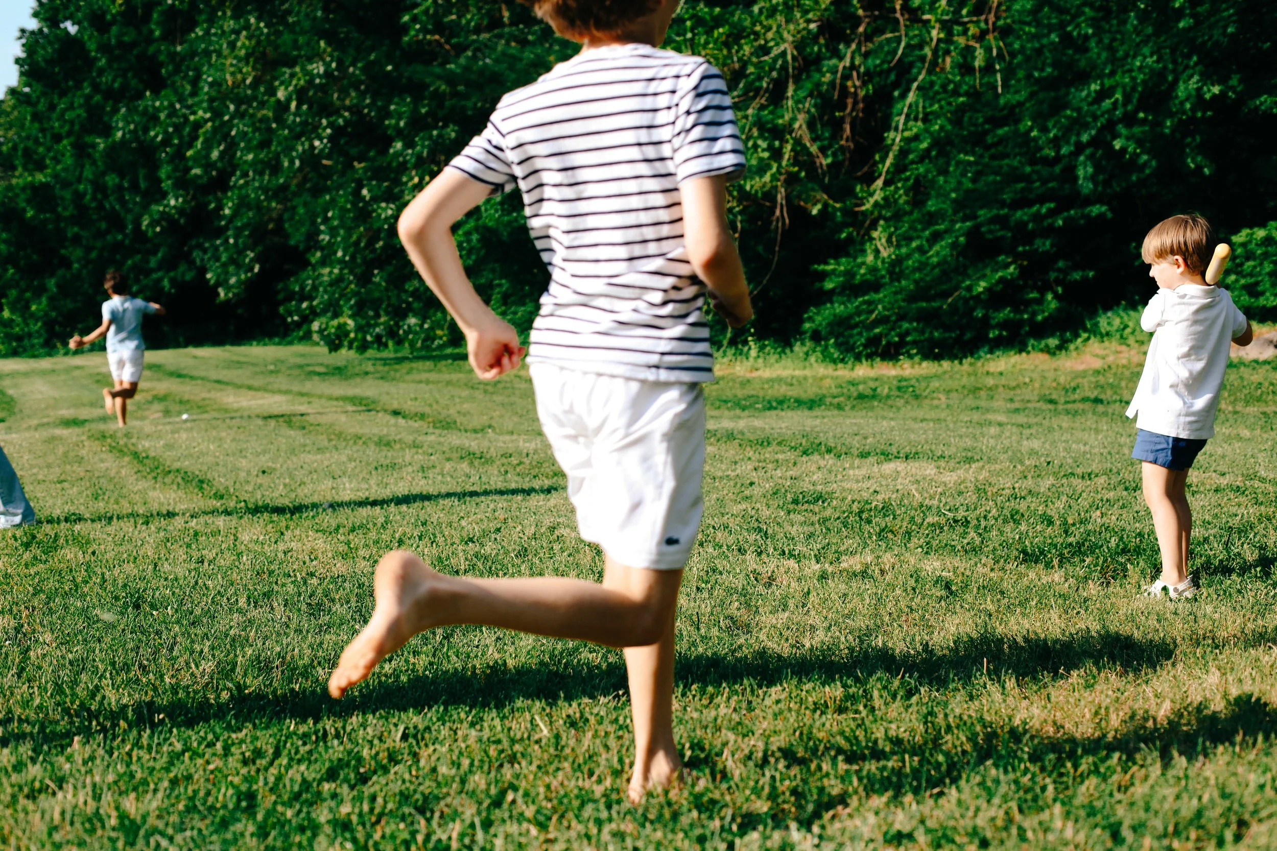 Children playing and running on a grassy field.