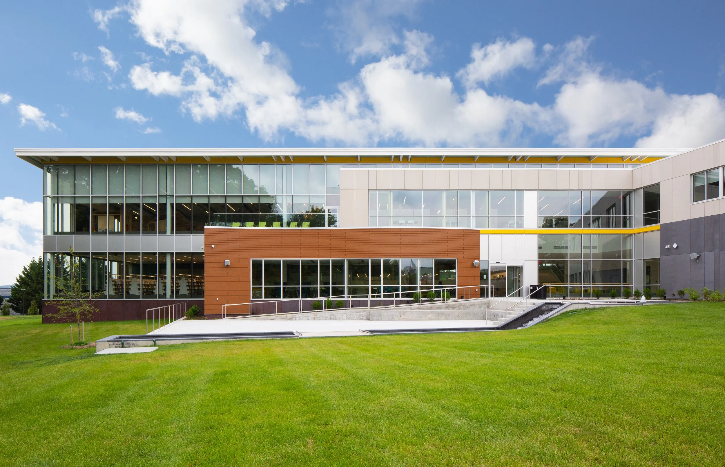 The new Cecil County Public Library North East Branch. Bright green lawn, blue sky, glass building facade.