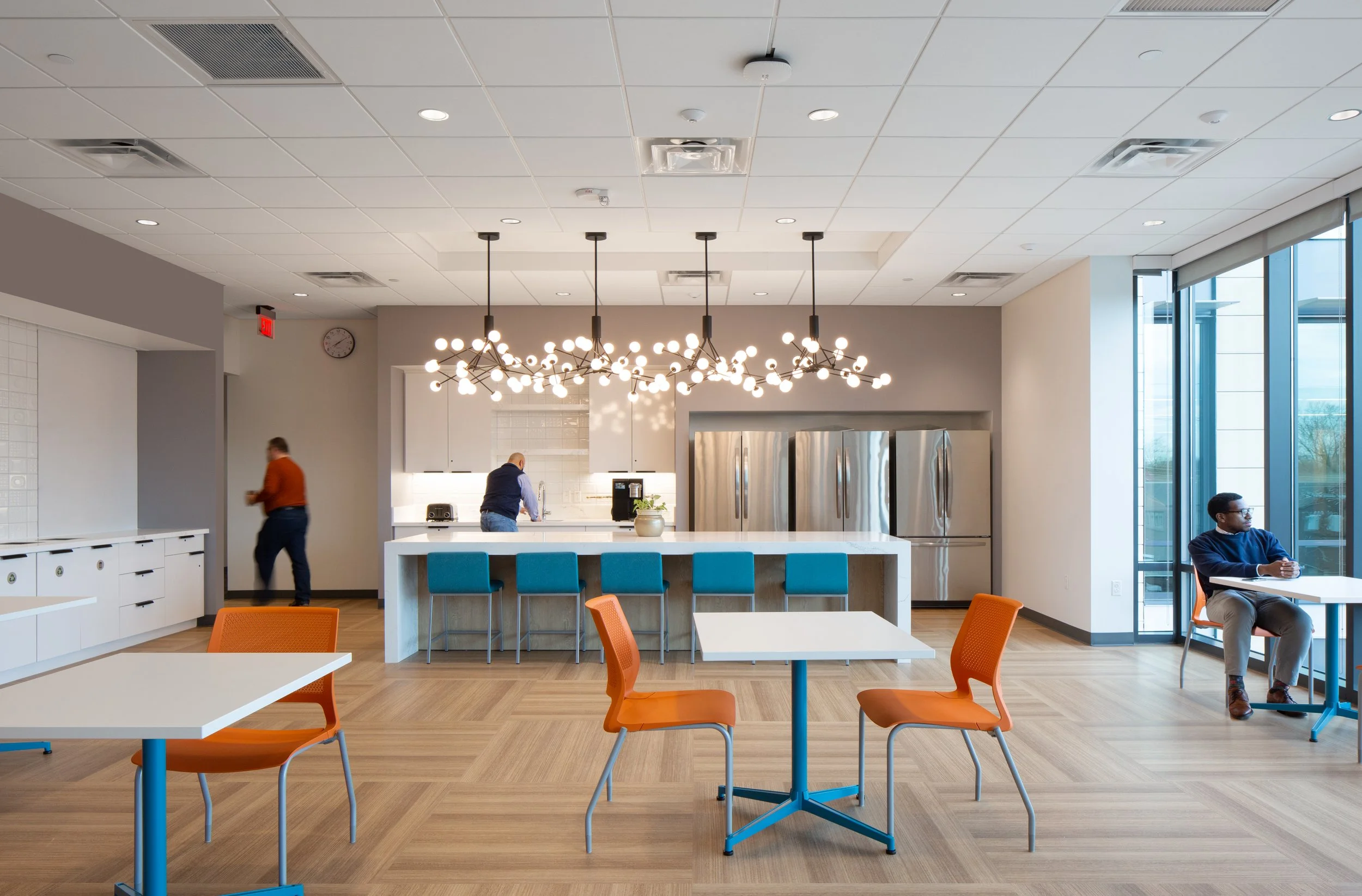 Modern kitchen interior with large windows, a lot of natural light. Bright white room with orange and blue accenting. College Park City Hall. Architecture.