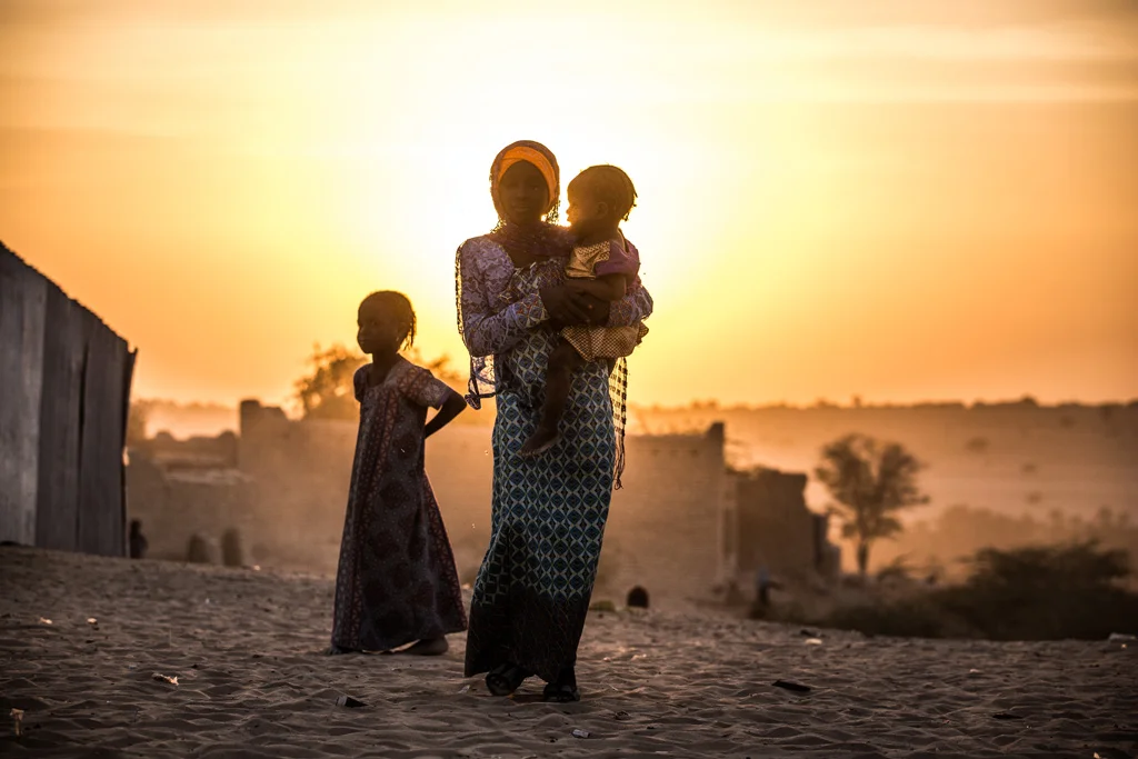 A girl carries her sister as another stands by her in the village of Mao in Chad. Photo: UNICEF/Tremeau