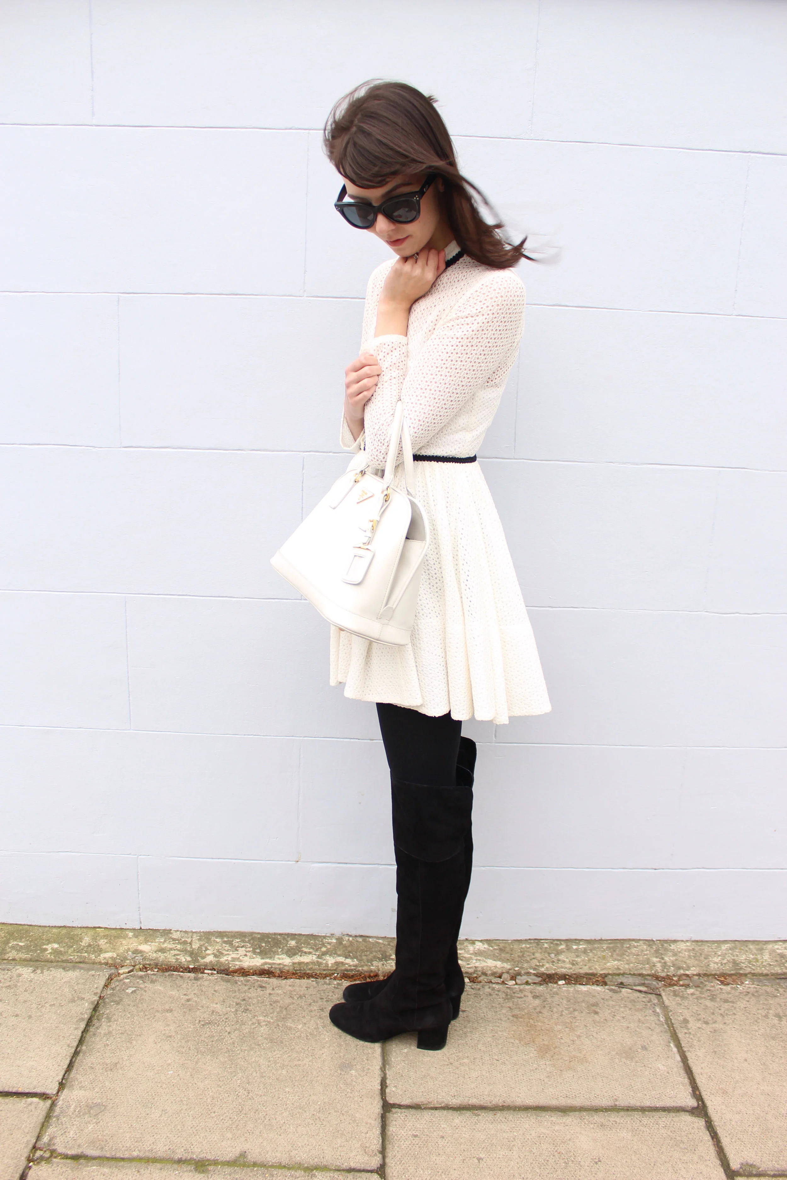 Wearing a white lace Maje dress and suede over the knee boots in Notting Hill.