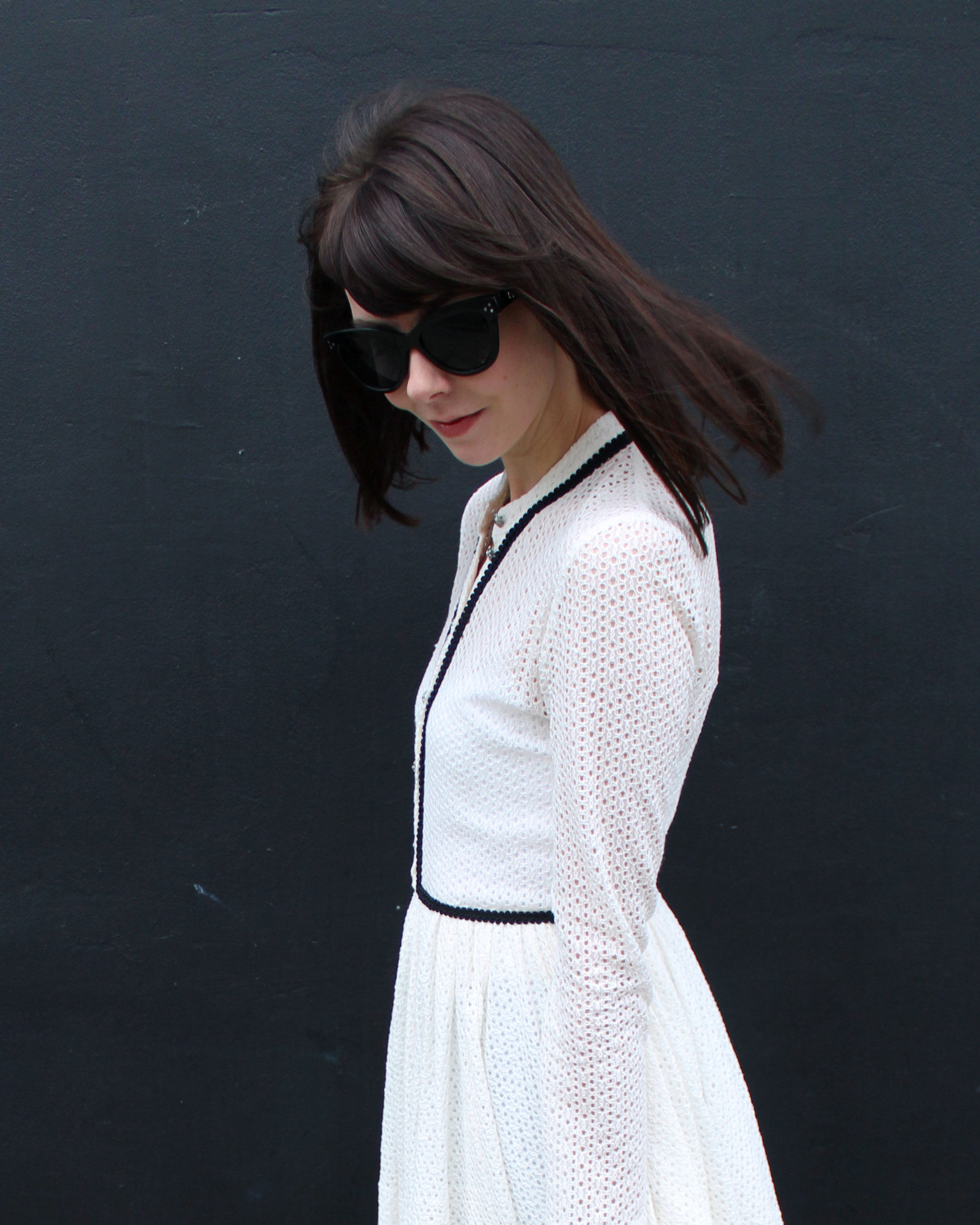 Wearing a white lace Maje dress and oversized black sunglasses.