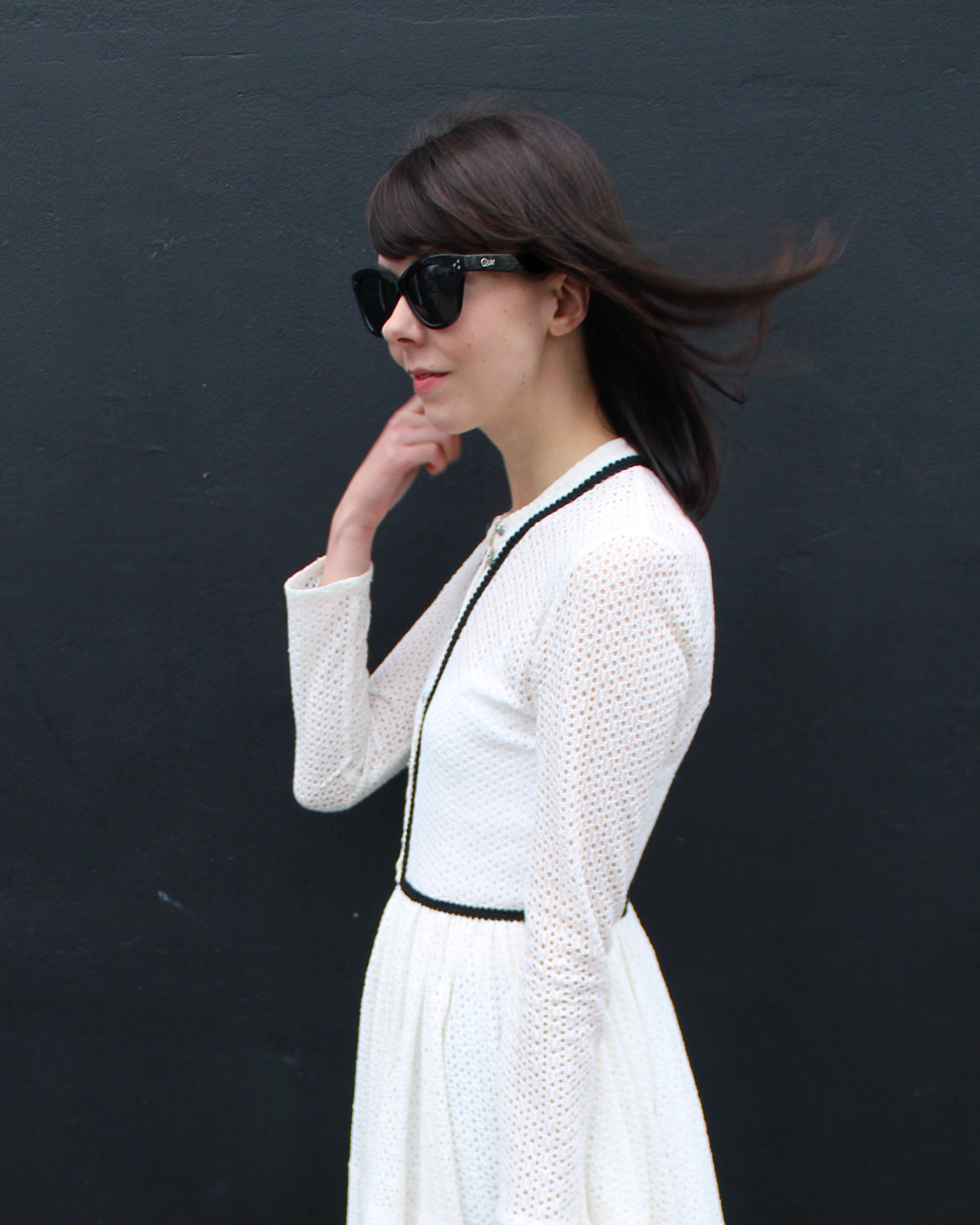 Wearing a white lace Maje dress and oversized black sunglasses.
