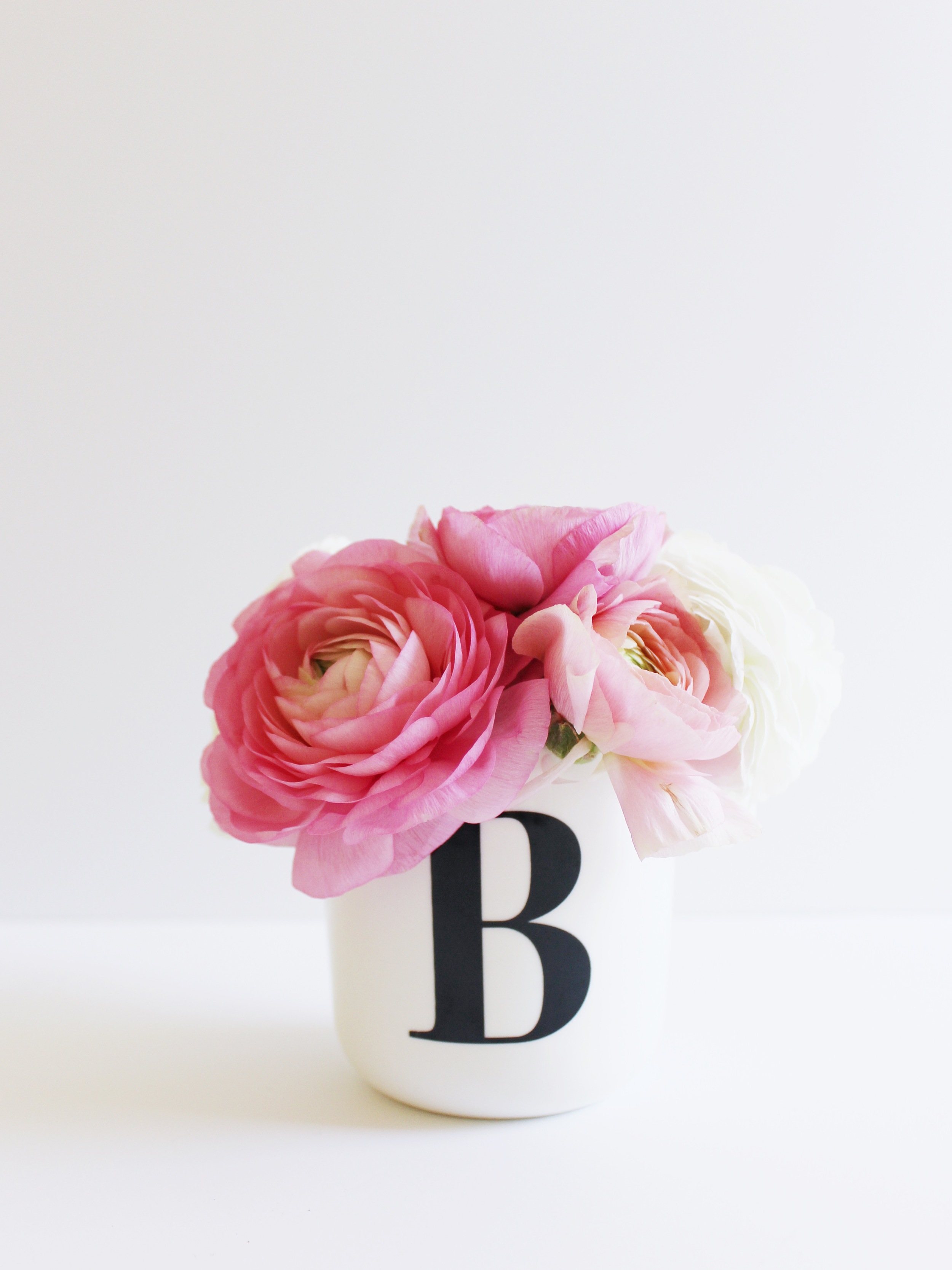 Pink and white ranunculus flowers in a monogrammed bud vase.