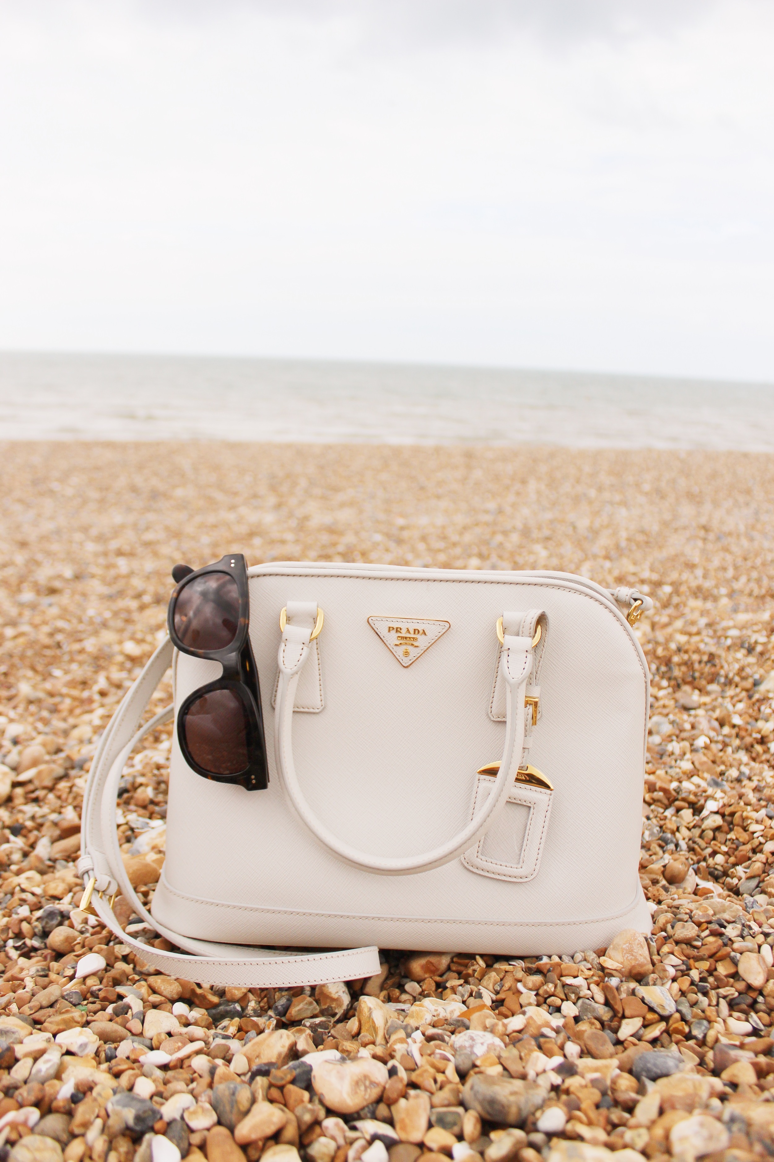 Prada bag and Madewell headliner sunglasses.