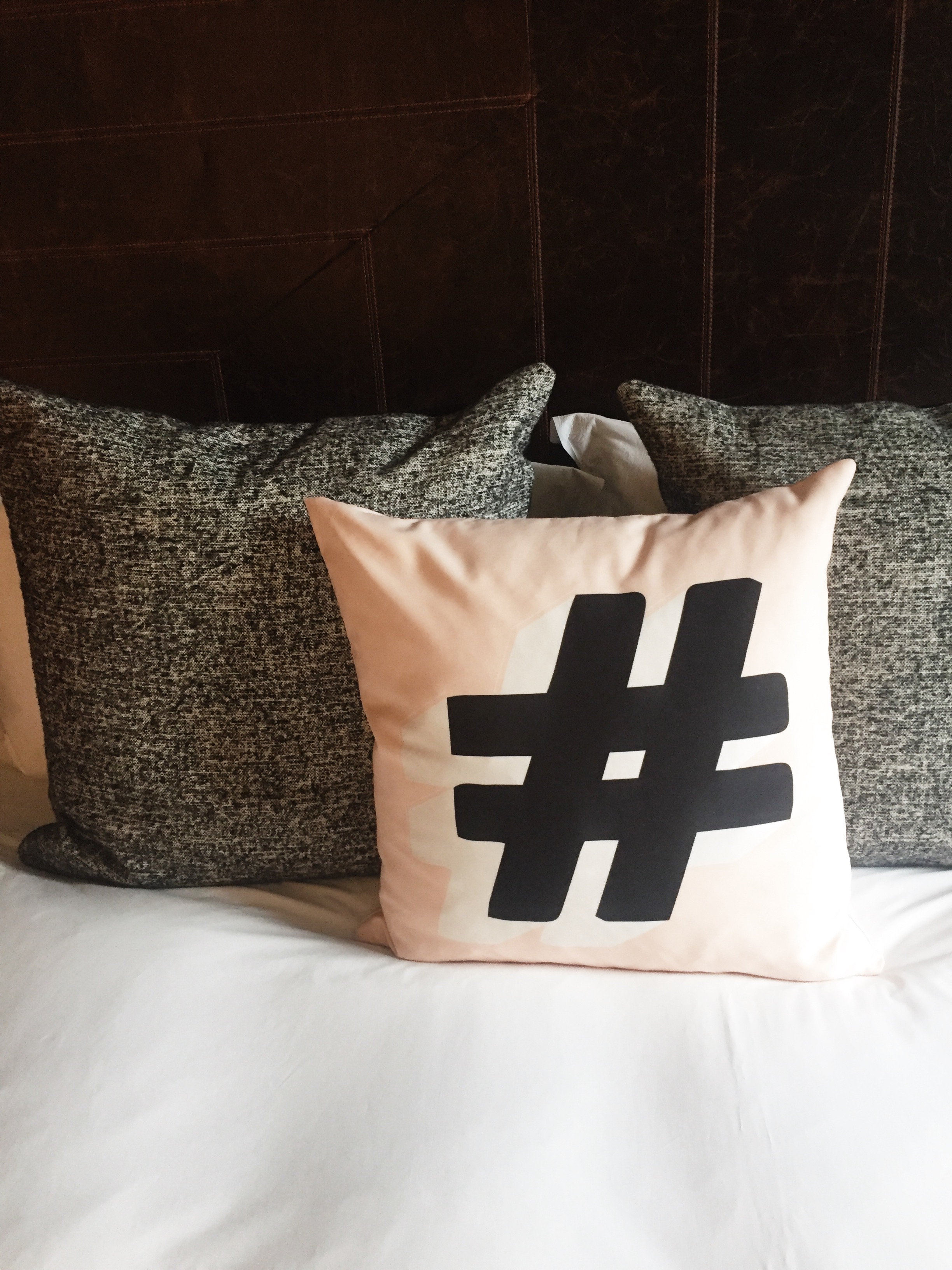 The bed, complete with blush pink hashtag pillow, at The Hoxton, Holborn.