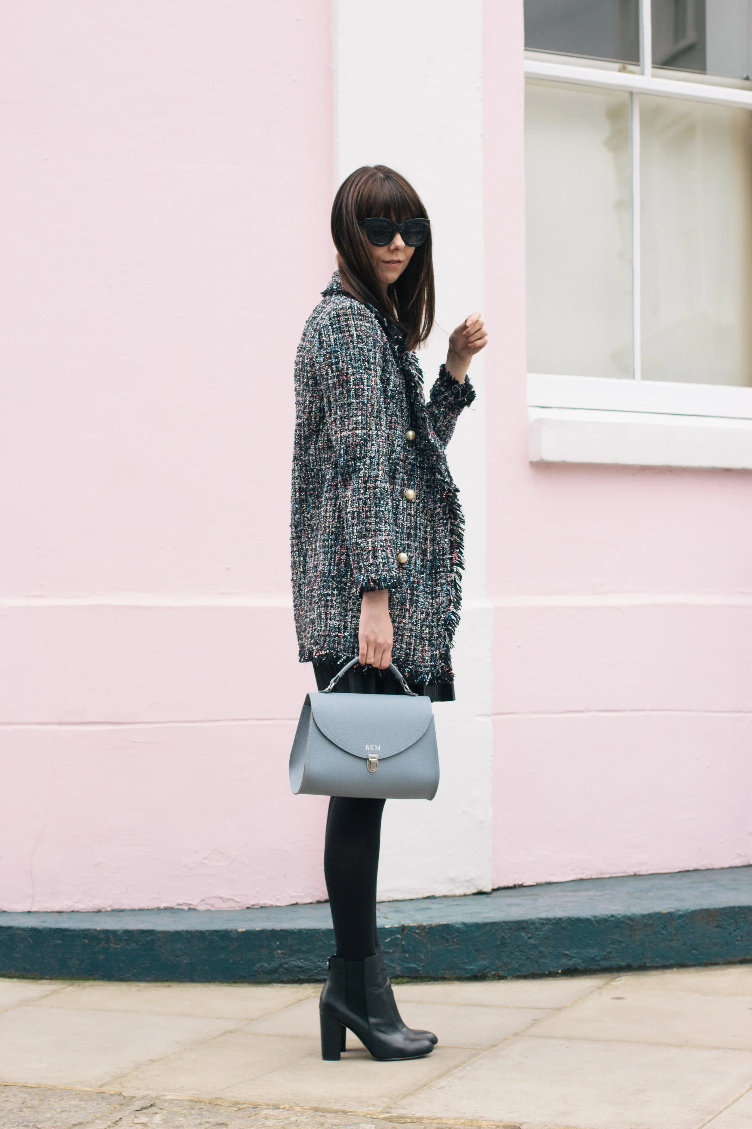 Wandering the colorful streets of Notting Hill wearing a Chanel lookalike jacket, a Cambridge Satchel Company bag, Sam Edelman booties and J.Crew pleated skirt | Pink House, Blue Bag | Sundays and Somedays