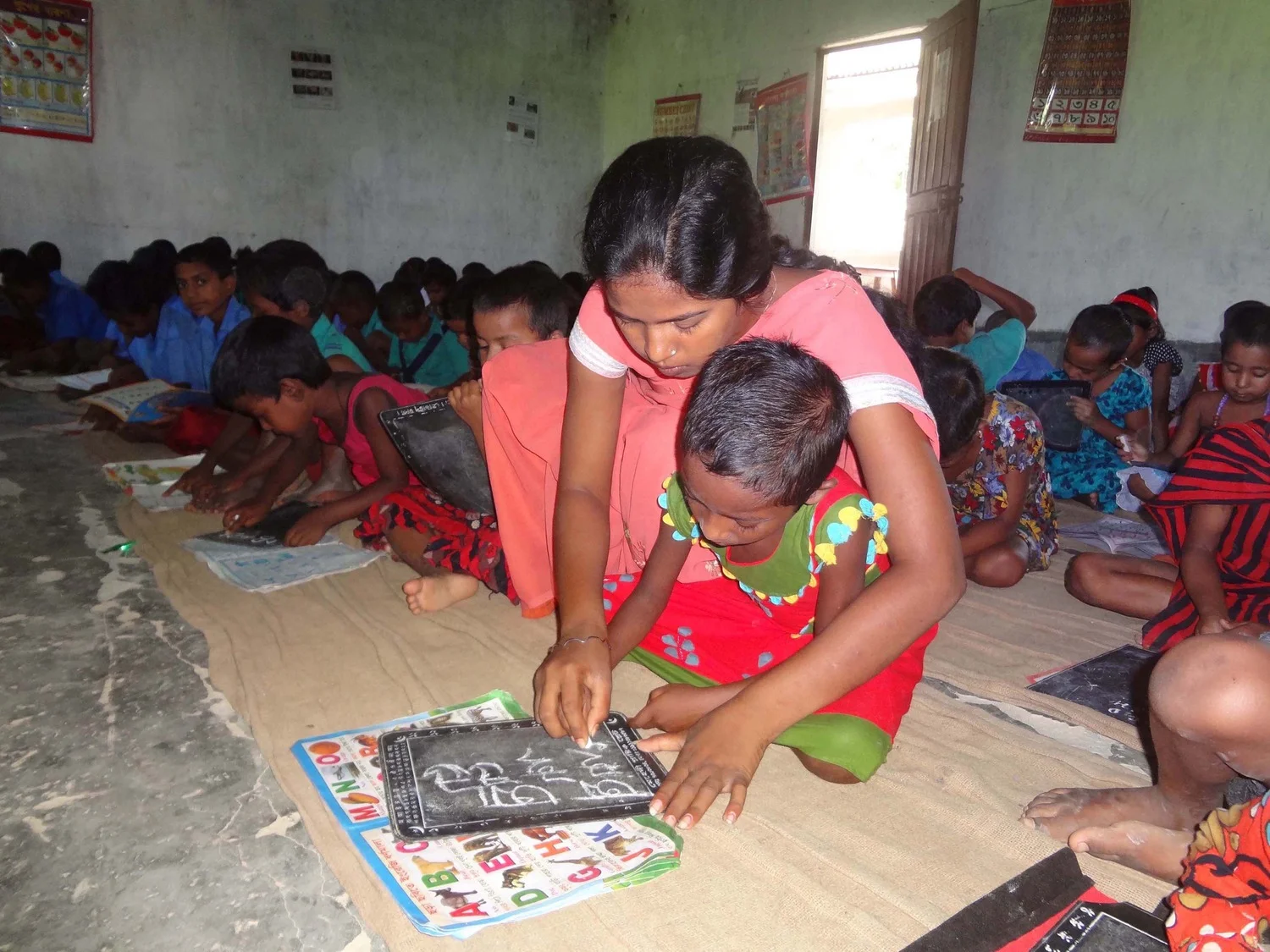 A+care+giver+teaches+Alphabet+to+child+in+Sambati.jpg