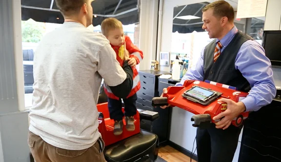 After the haircut is finished, clean off the child, remove the tray and have the parent safely remove the child.