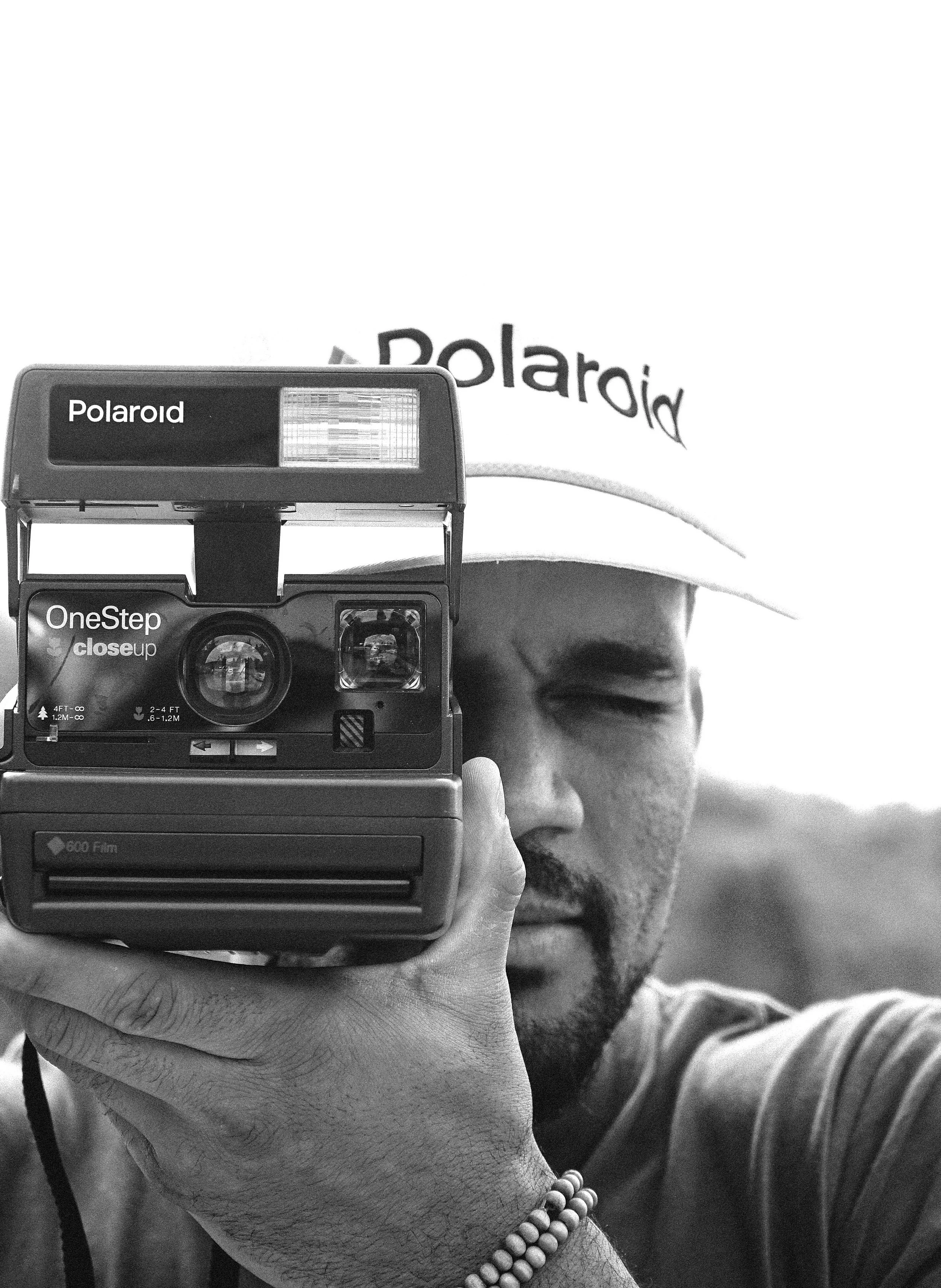 Close up black and white portrait with Polaroid camera and hat