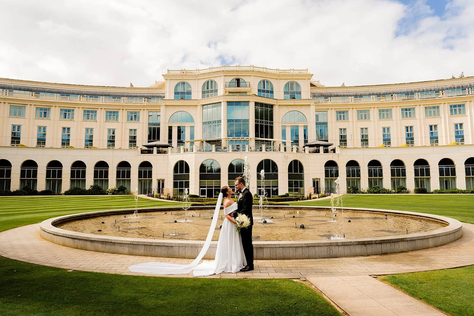 couple in front of the back of Powerscourt hotel and fountain