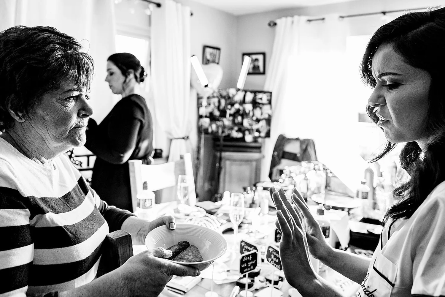 Black and white photograph of a guest offering a bowl to a bride as she gets ready on the wedding morning