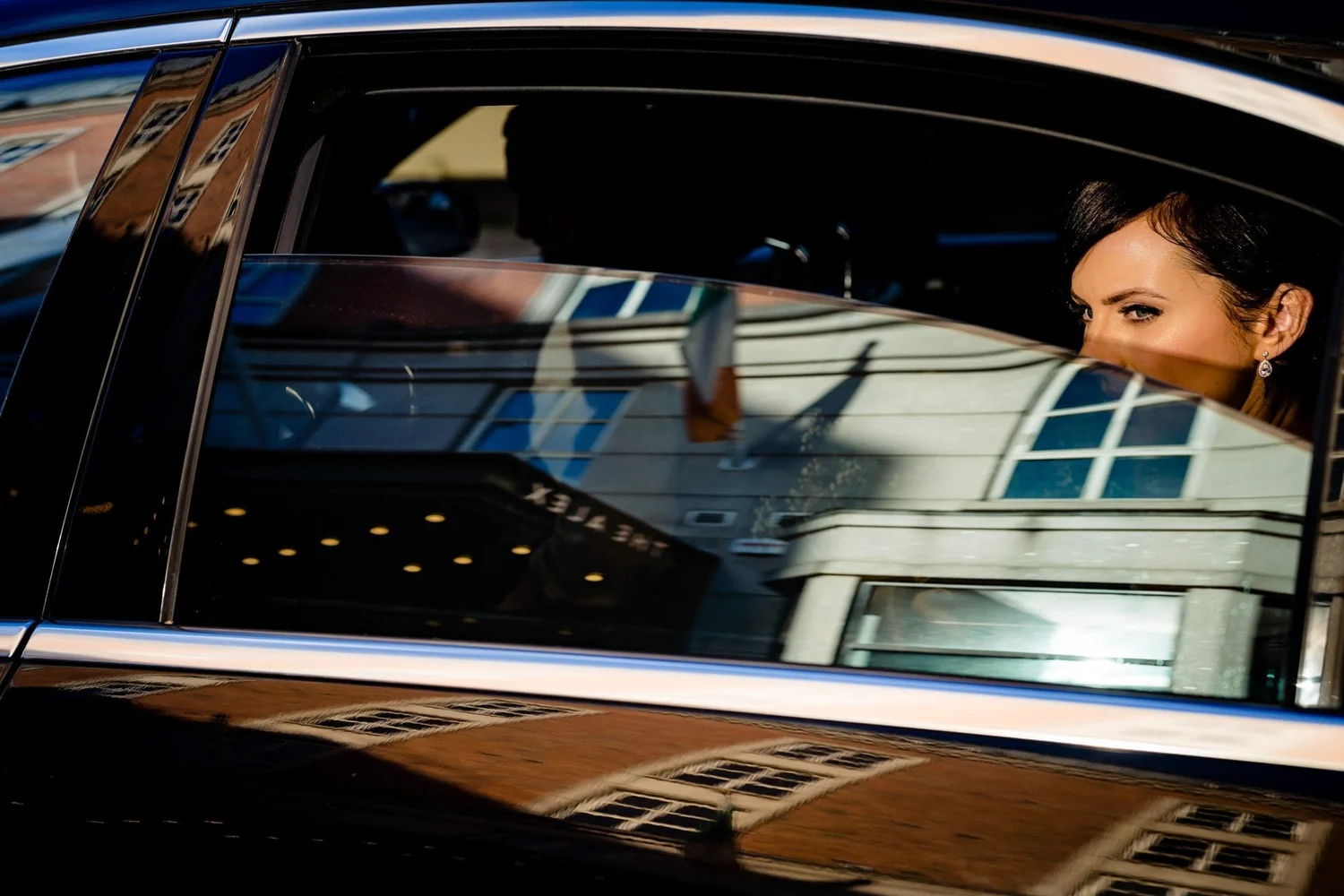 Bride looking out from a car window with Dublin buildings reflected in the glass