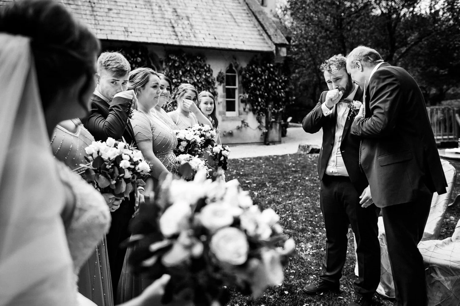 Black and white photograph of two guests wiping their eyes during an outdoor ceremony