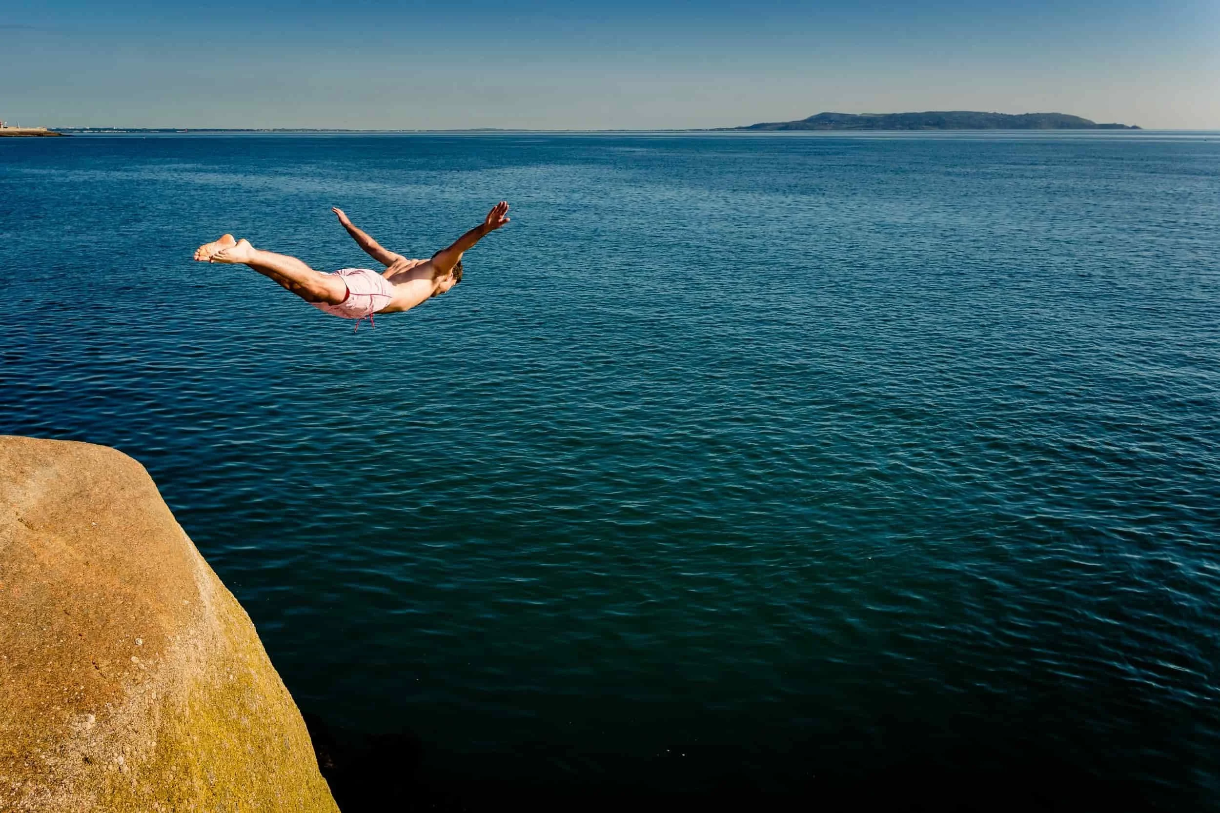 Swimmer diving from the rocks into the sea at the Forty Foot in Dún Laoghaire on a wedding morning