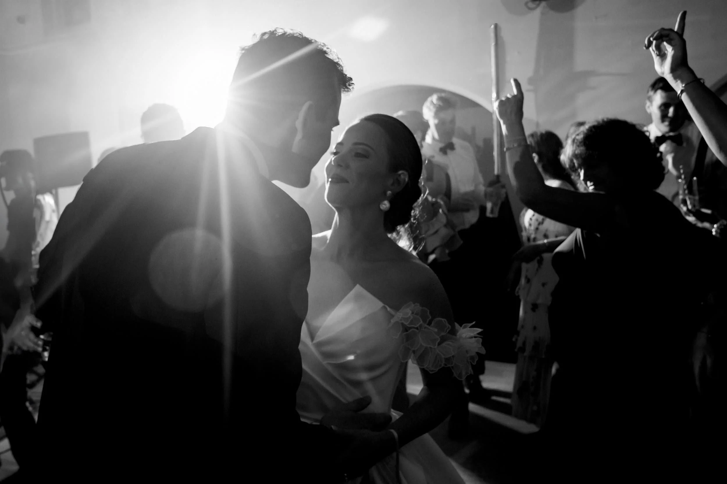 Black and white photograph of a couple about to kiss on a crowded, backlit dance floor at Gloster House