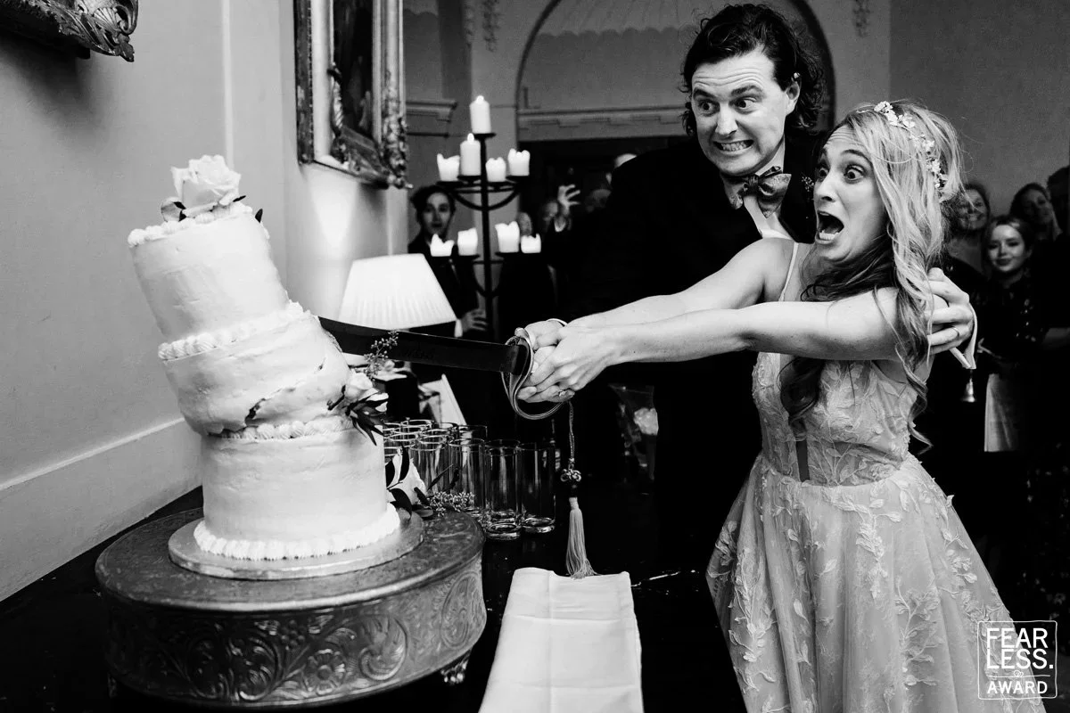 black and white photograph of couple cutting a cake and it collapses