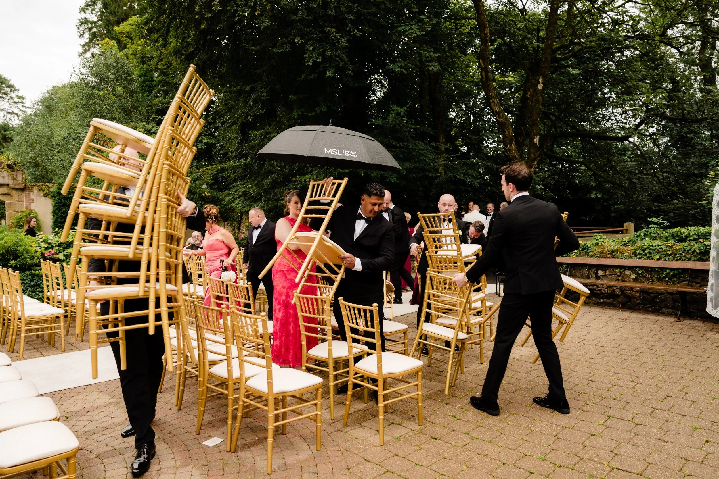 galgorm-wedding-photographer-holly-matt-27-chairs-carried-indoors-from-the-rain.jpg