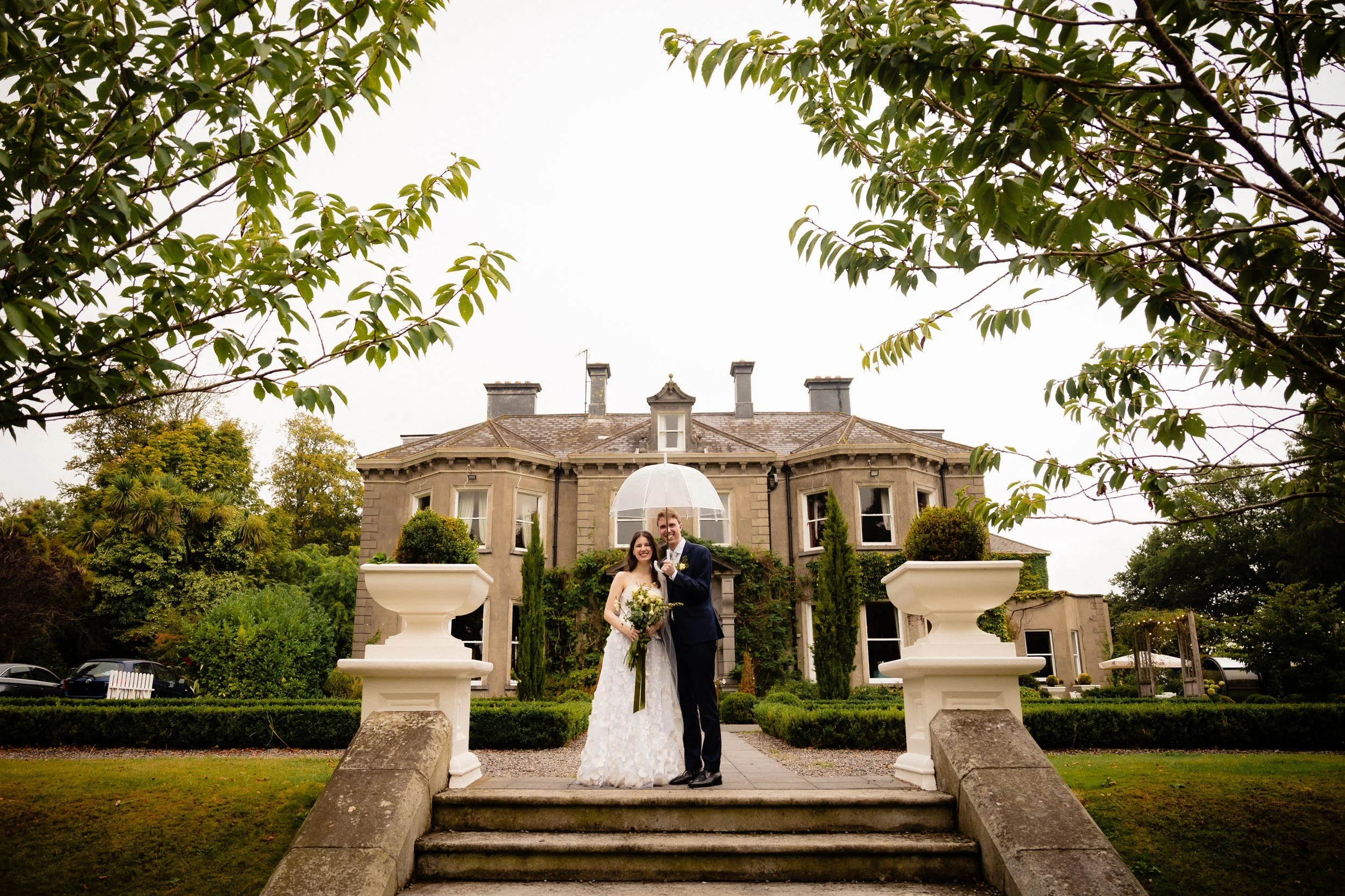 tinakilly-wedding-photographer-laura-james-48-under-an-umbrella-in-front-of-the-house.jpg