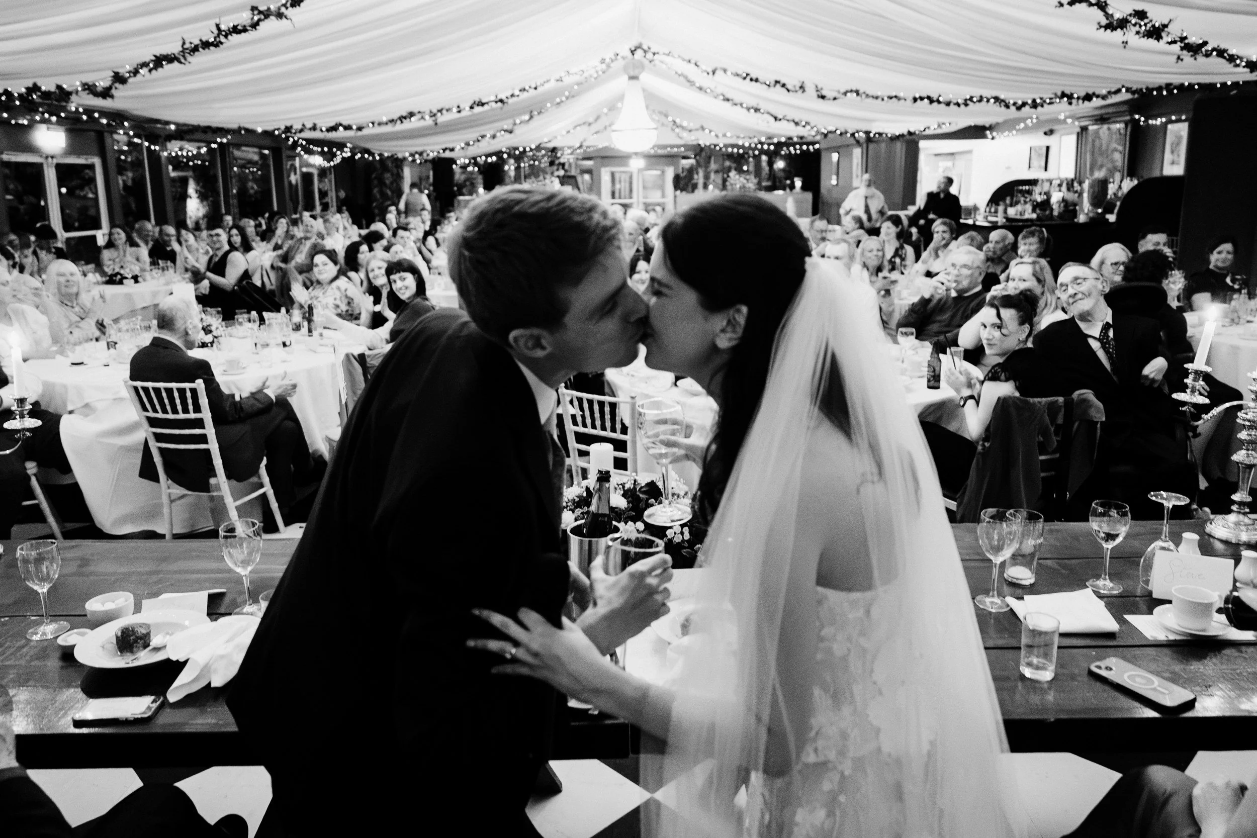 tinakilly-wedding-photographer-laura-james-66-kiss-at-the-table.jpg