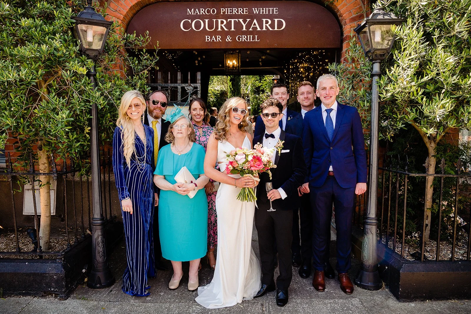 marco-pierre-white-wedding-photographer-elle-iain-51-family-photo-under-the-courtyard-sign.jpg