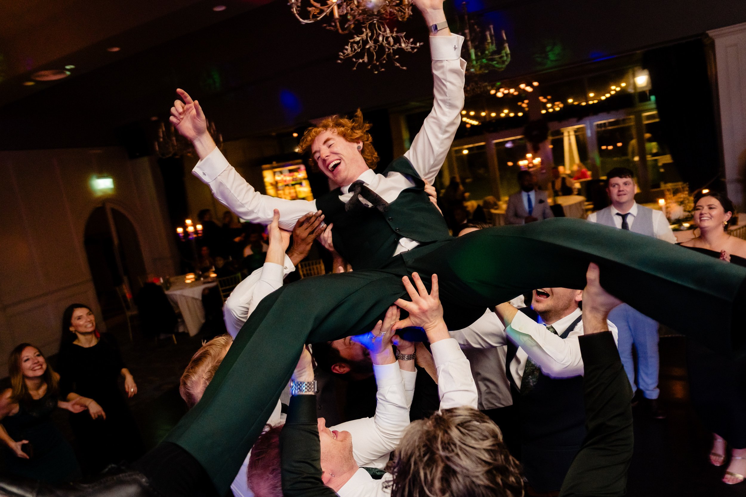 Guests lifting the groom into the air on the dance floor
