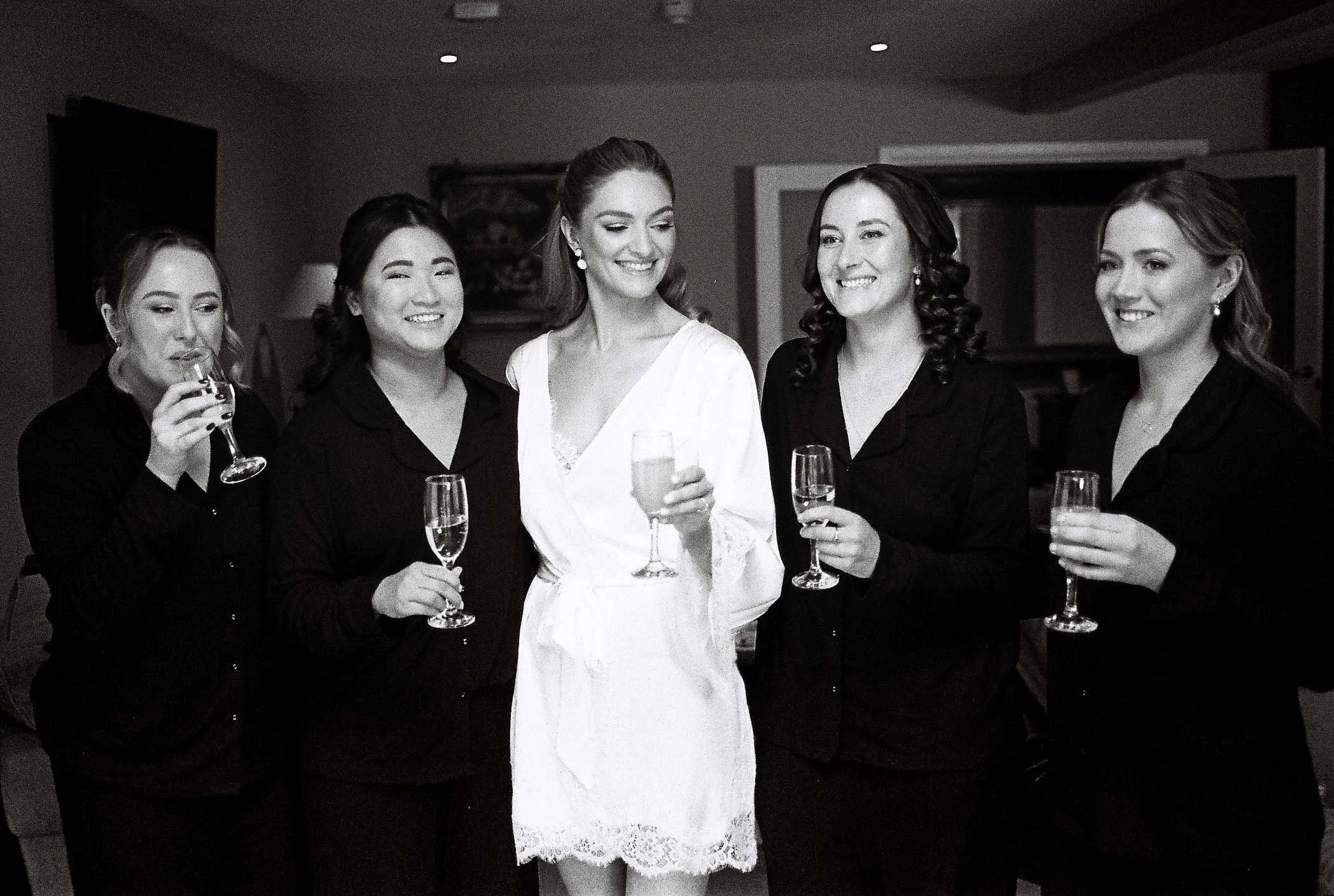 bridesmaids in black and white cheering together in the morning