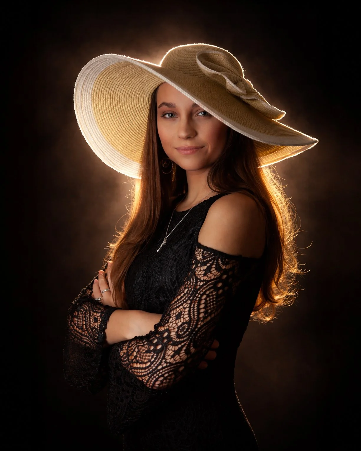 A young woman with long wavy hair wearing a large sunhat with a bow, a black lace dress with open shoulders, and jewelry, standing against a dark background with backlighting.