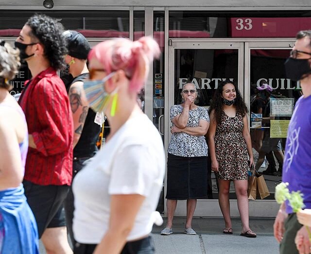 Women watch from the sidewalk on Haywood Street as hundreds march in Asheville June 28, 2020, in honor of the 51st anniversary of the Stonewall Riots. Organizers said the gathering would not have been possible without the Stonewall event and urged ot