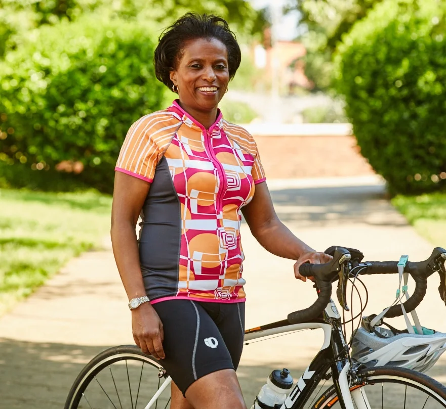 Woman wearing Pedal Beat Cycling Jersey Standing Next to Bike