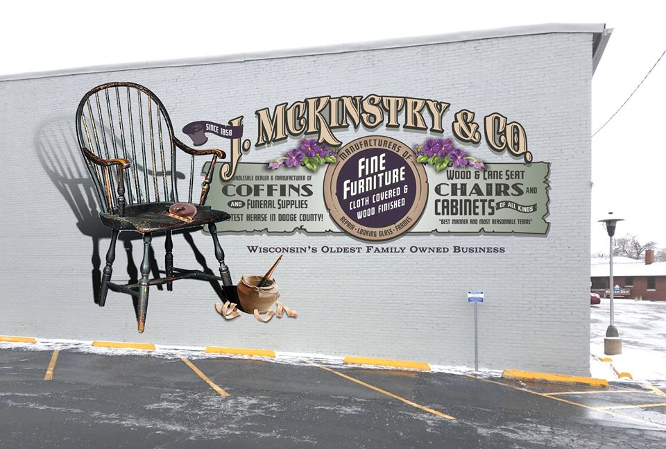 14. Project Leader: Noella Cotham and Elaine Wallis Subject: McKinstry's & Co. Champion: McKinstry's Home Furnishings Location: McKinstry's Warehouse Born in Quebec, Canada, John McKinstry set up business in Beaver Dam in 1855 making furniture and caskets for early settlers. The business included a funeral home. Fred MacMurray of Hollywood fame worked in the store while a high school student. He used the tape measure painted on the chair in the mural, the chair being the first manufactured by the business. The glue pot in the mural also represents the kind actually used in the business’ early days.